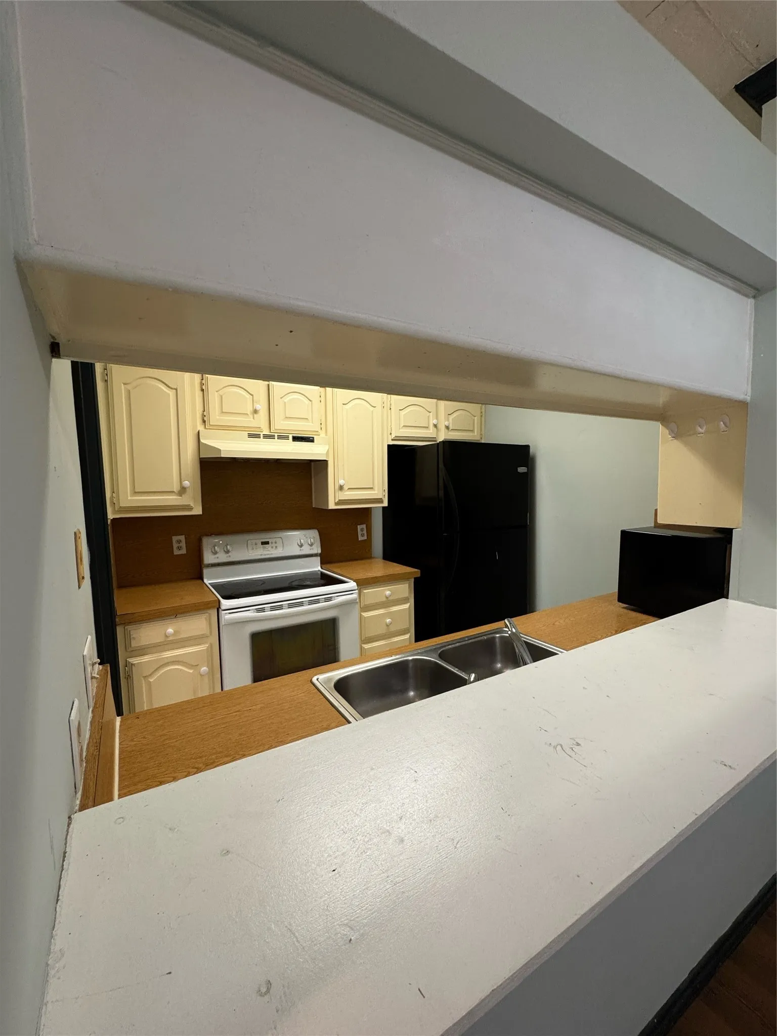Kitchen featuring a dual basin stainless steel sink, wood-finish countertops, and cream-colored cabinetry