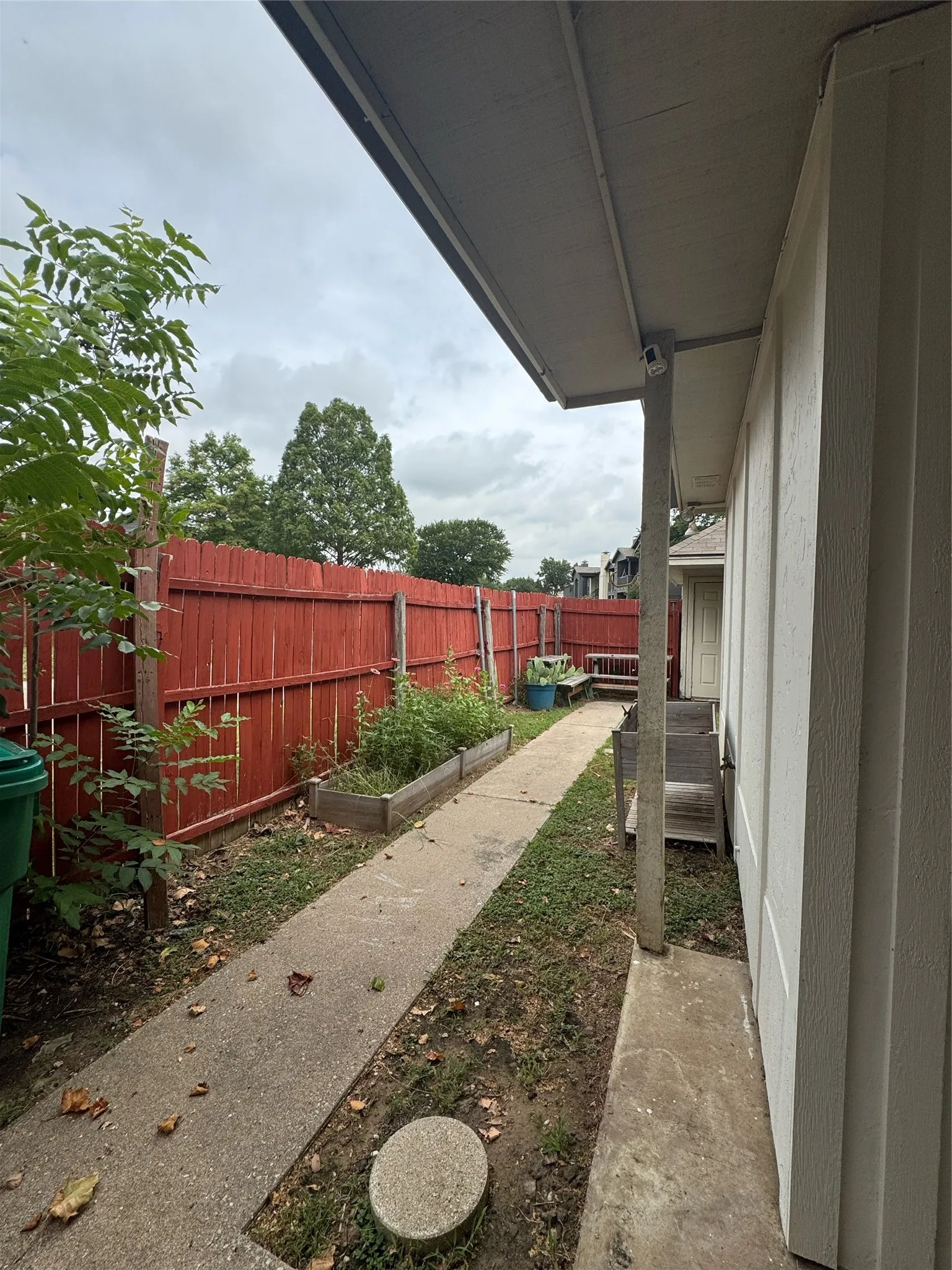 Side yard featuring a red privacy fence and concrete pathway