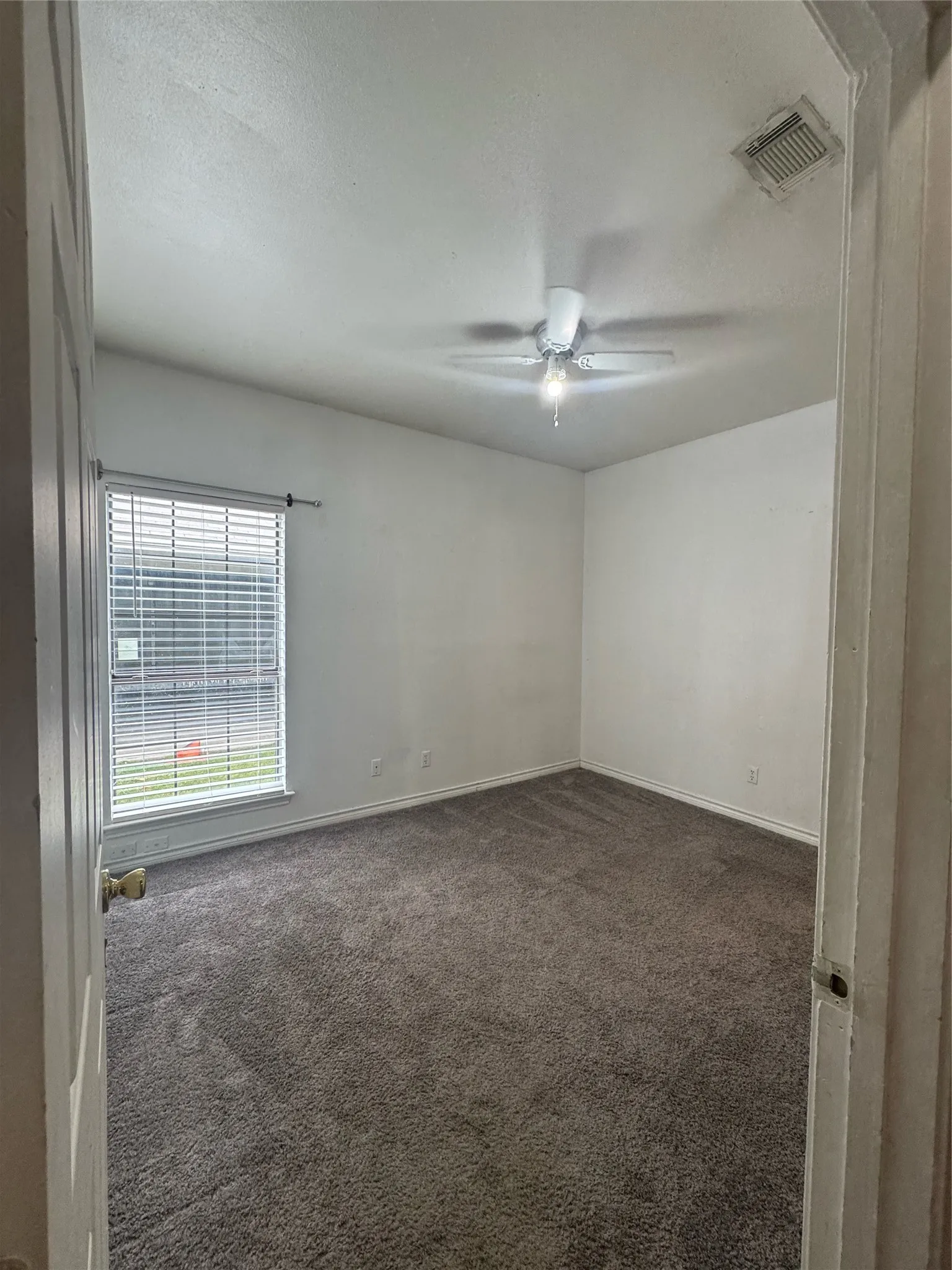 Carpeted room featuring a ceiling fan with integrated lighting, a window with horizontal blinds, and white painted walls