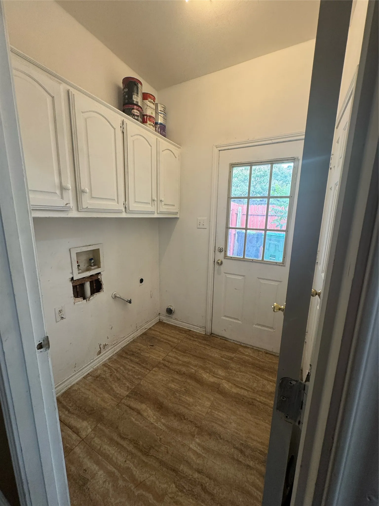 Utility space featuring wood-finish flooring, white cabinetry, and a glass-paneled exterior door