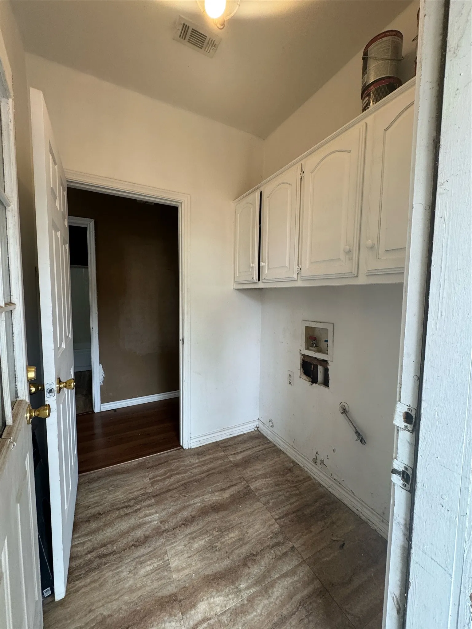 Dedicated utility room featuring wood-finish flooring and white upper cabinetry
