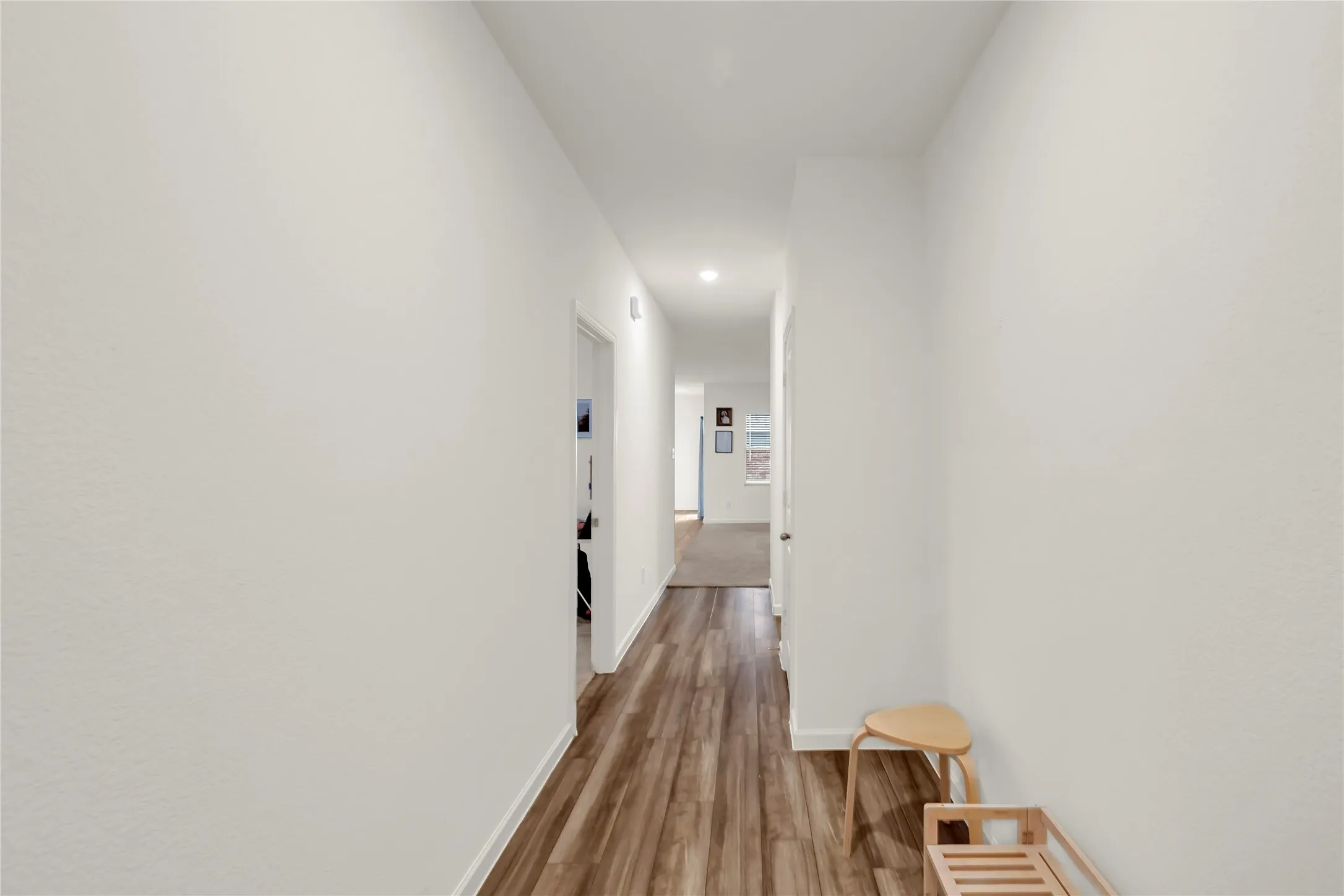 Hallway featuring wood-finish flooring, white walls, and recessed lighting