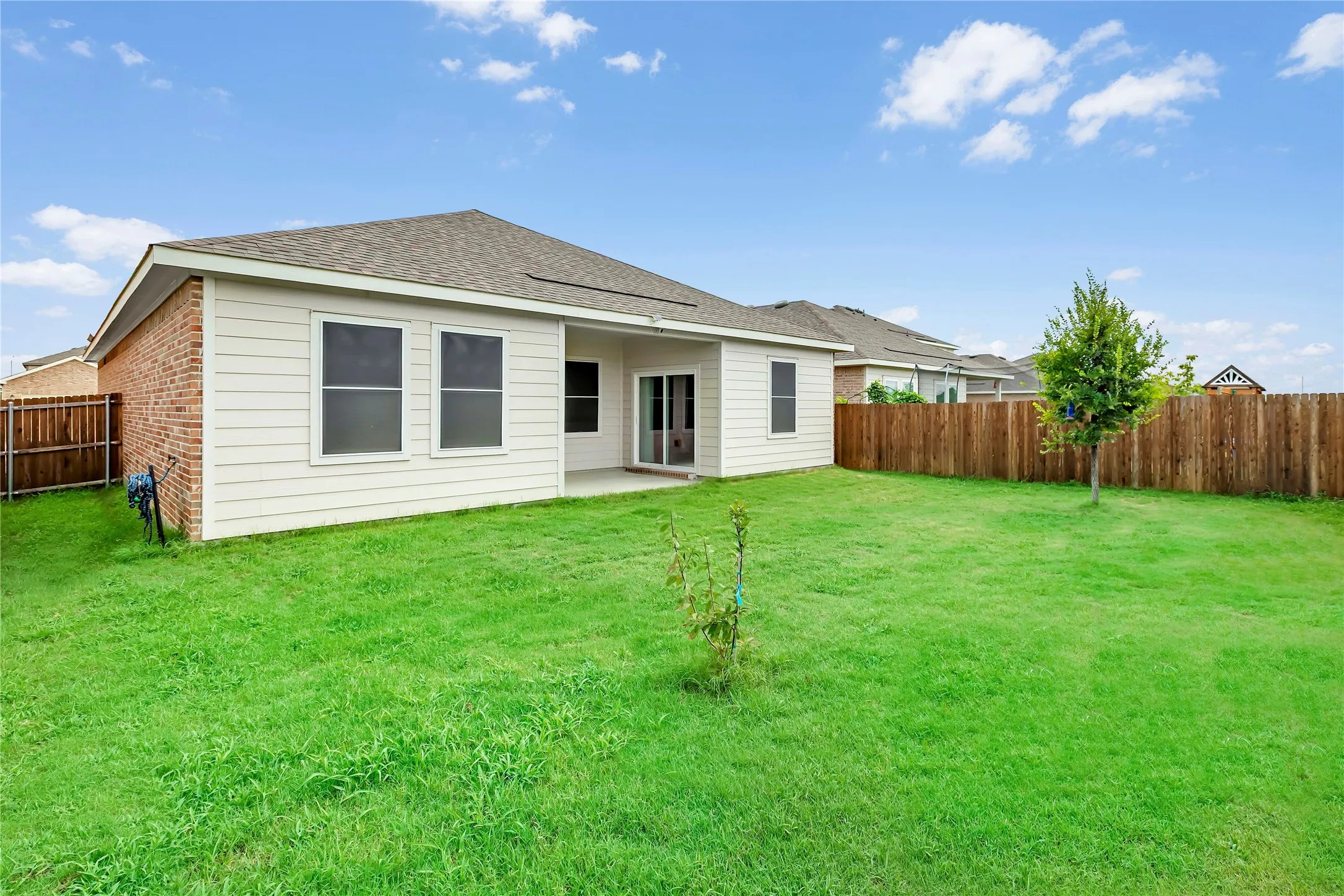 Expansive backyard featuring a manicured lawn, wood privacy fencing, and a concrete patio