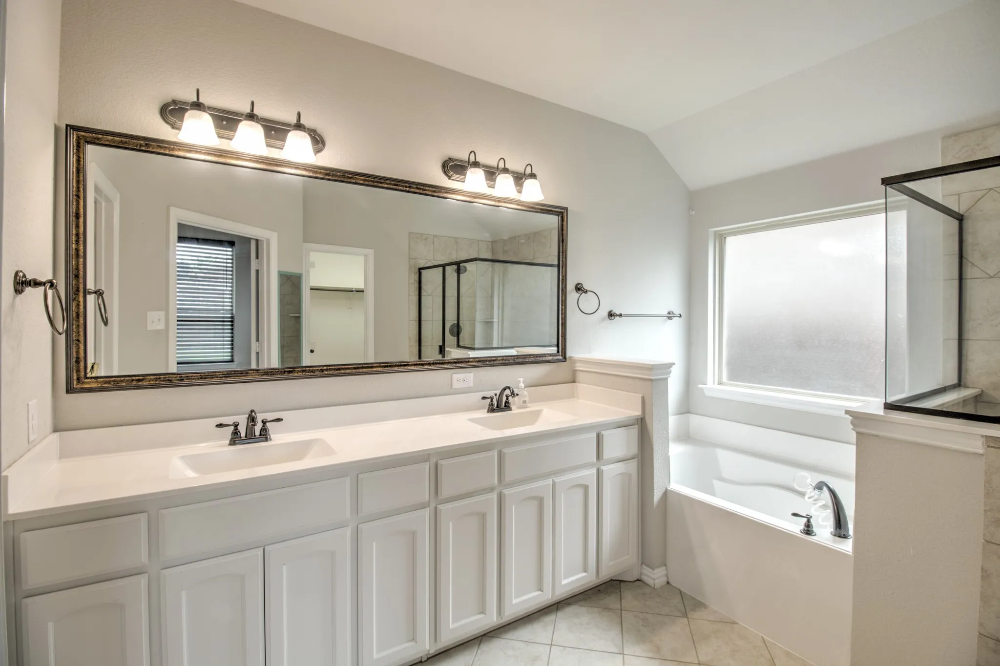 Bathroom featuring a dual vanity with white cabinetry, light-toned countertops, and a full-width mirror