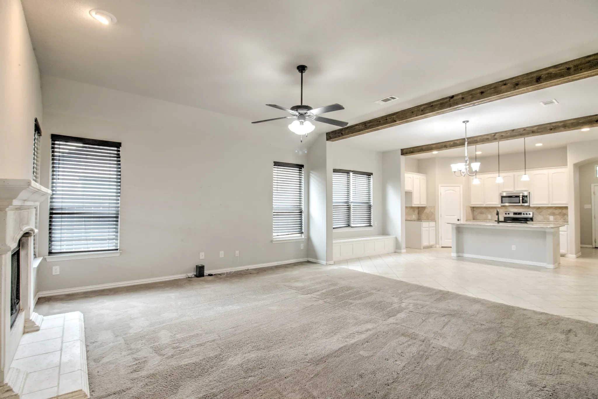 Expansive living area featuring vaulted ceilings, a ceiling fan with light fixture, and a tiled fireplace