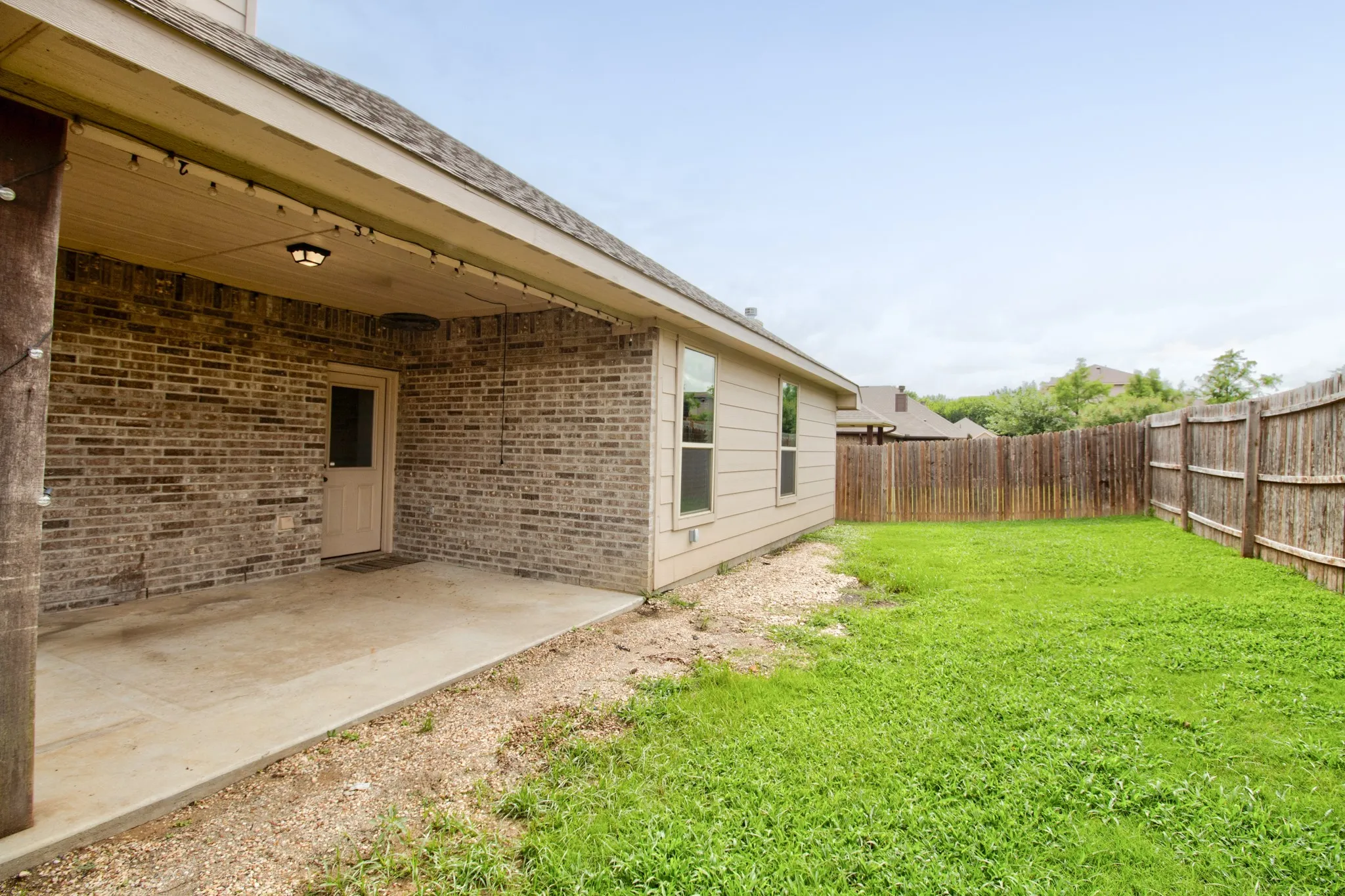 Covered patio featuring a concrete slab and brick exterior