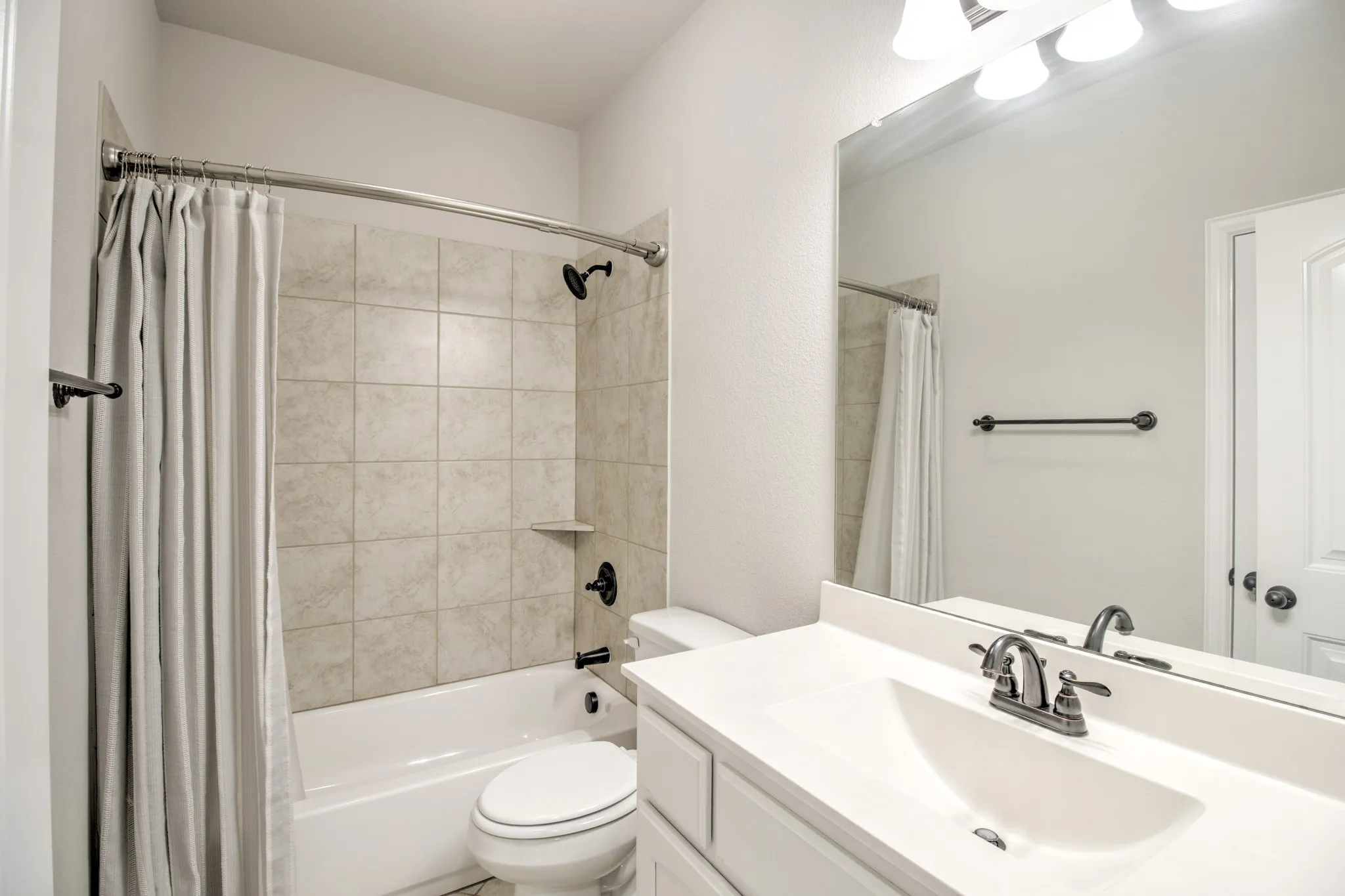 Bathroom featuring a white vanity with an integrated sink, polished chrome faucet, and a large mirror