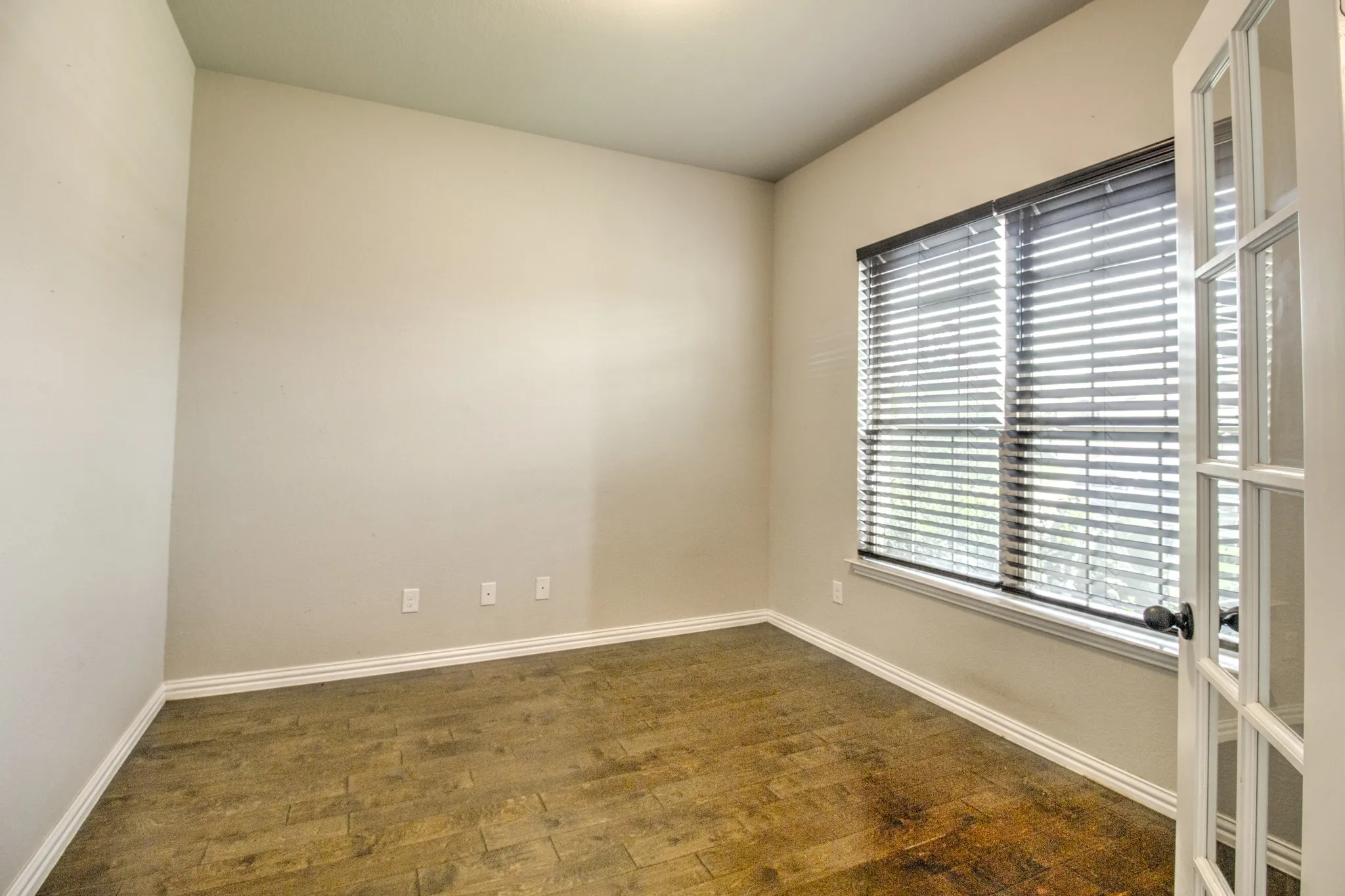Room featuring wood-finish flooring, neutral wall paint, and white baseboards