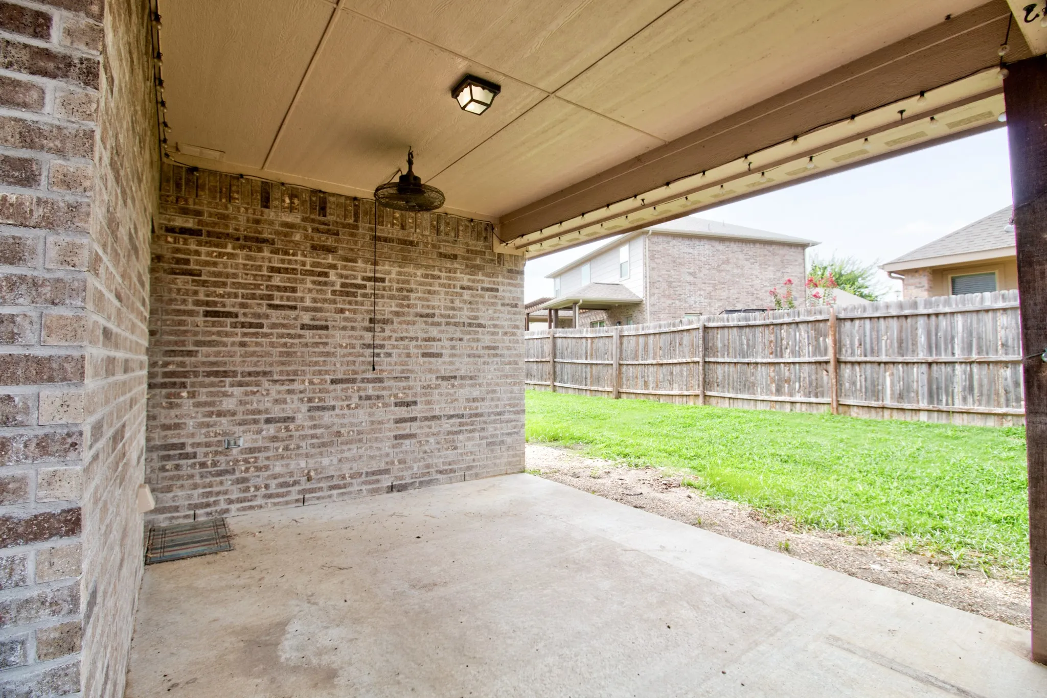 Covered patio featuring a concrete slab and brick exterior wall