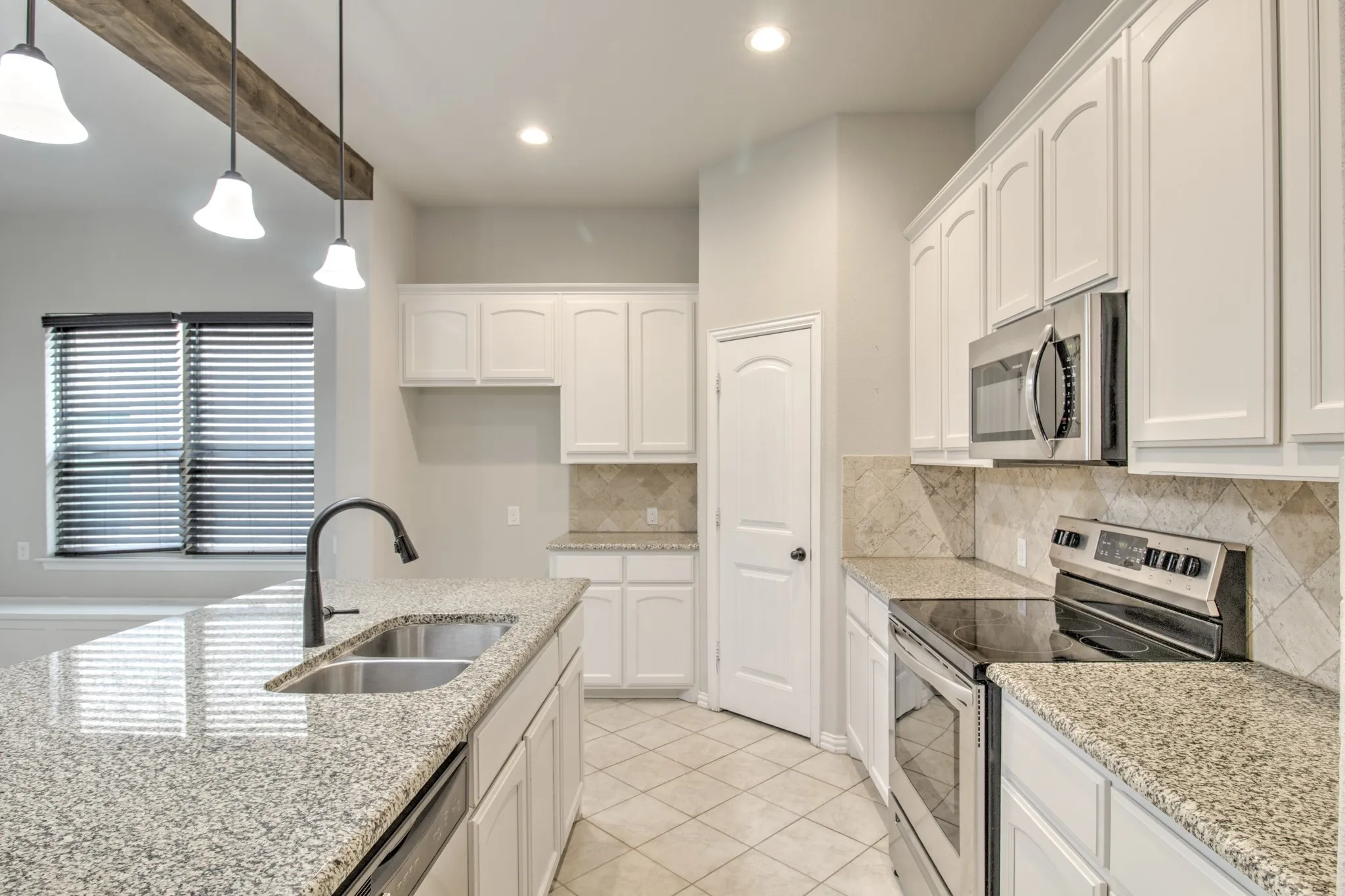 Kitchen featuring granite countertops, white cabinetry, stainless steel appliances, tile backsplash, and a wood beam accent with pendant lighting