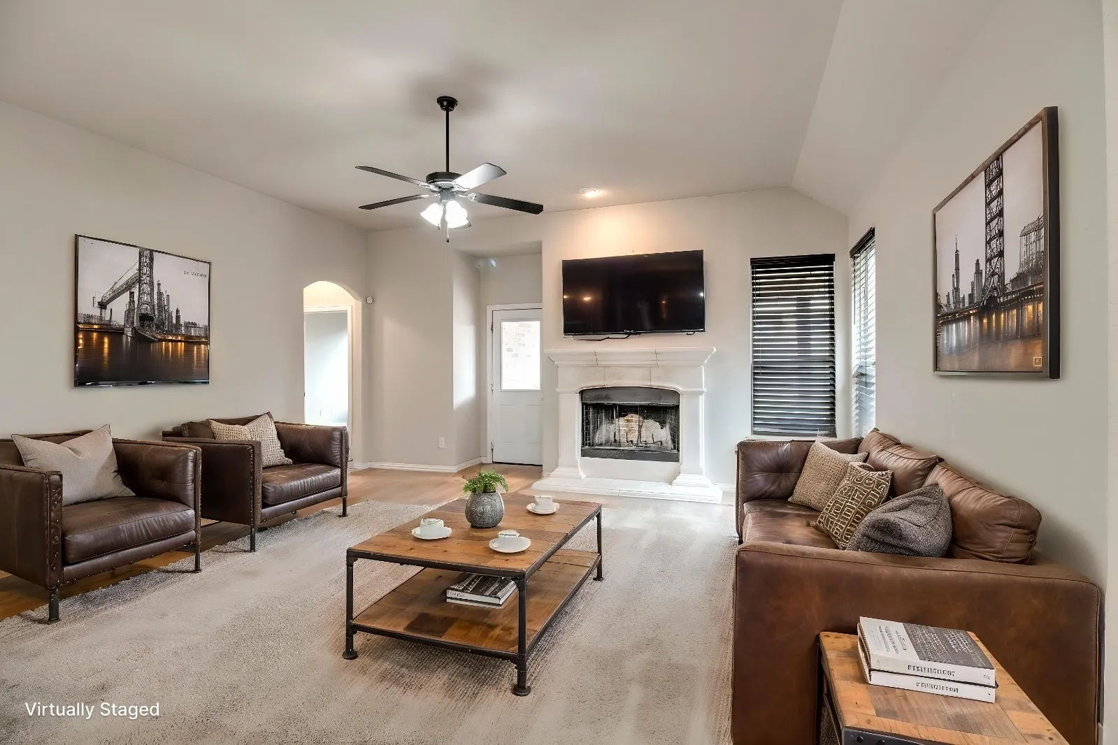 Living area featuring a ceiling fan, arched doorway, fireplace with mantel, and wood-finish flooring