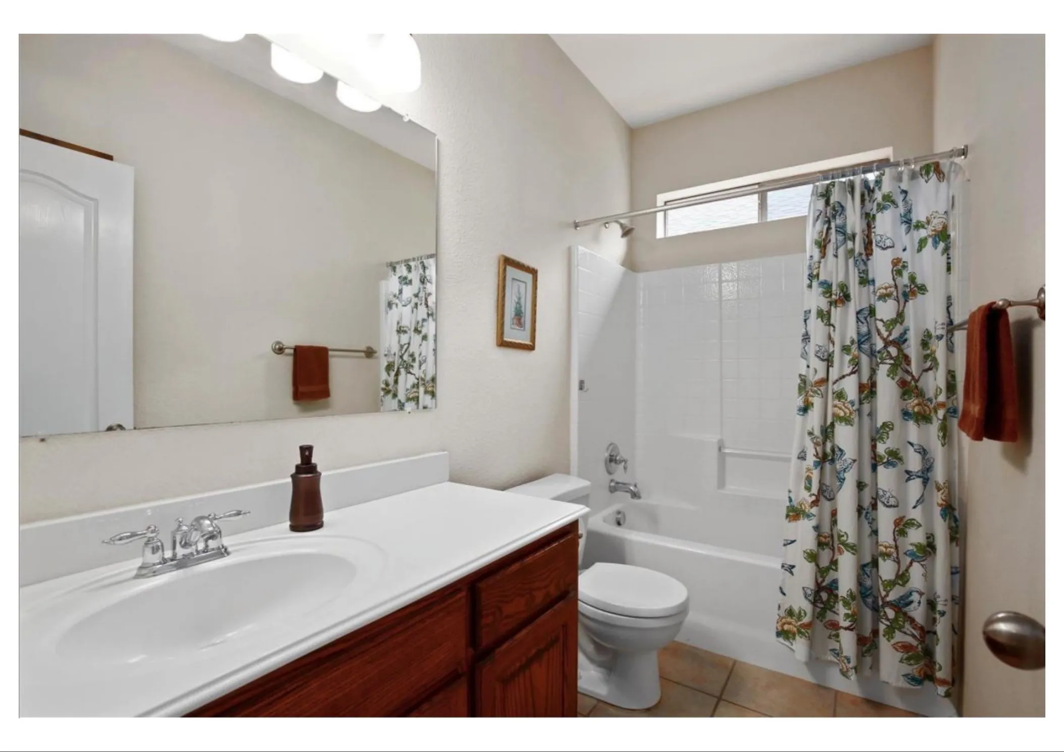 Full bathroom featuring a single vanity with wood-finish cabinetry, a white countertop, and a chrome faucet