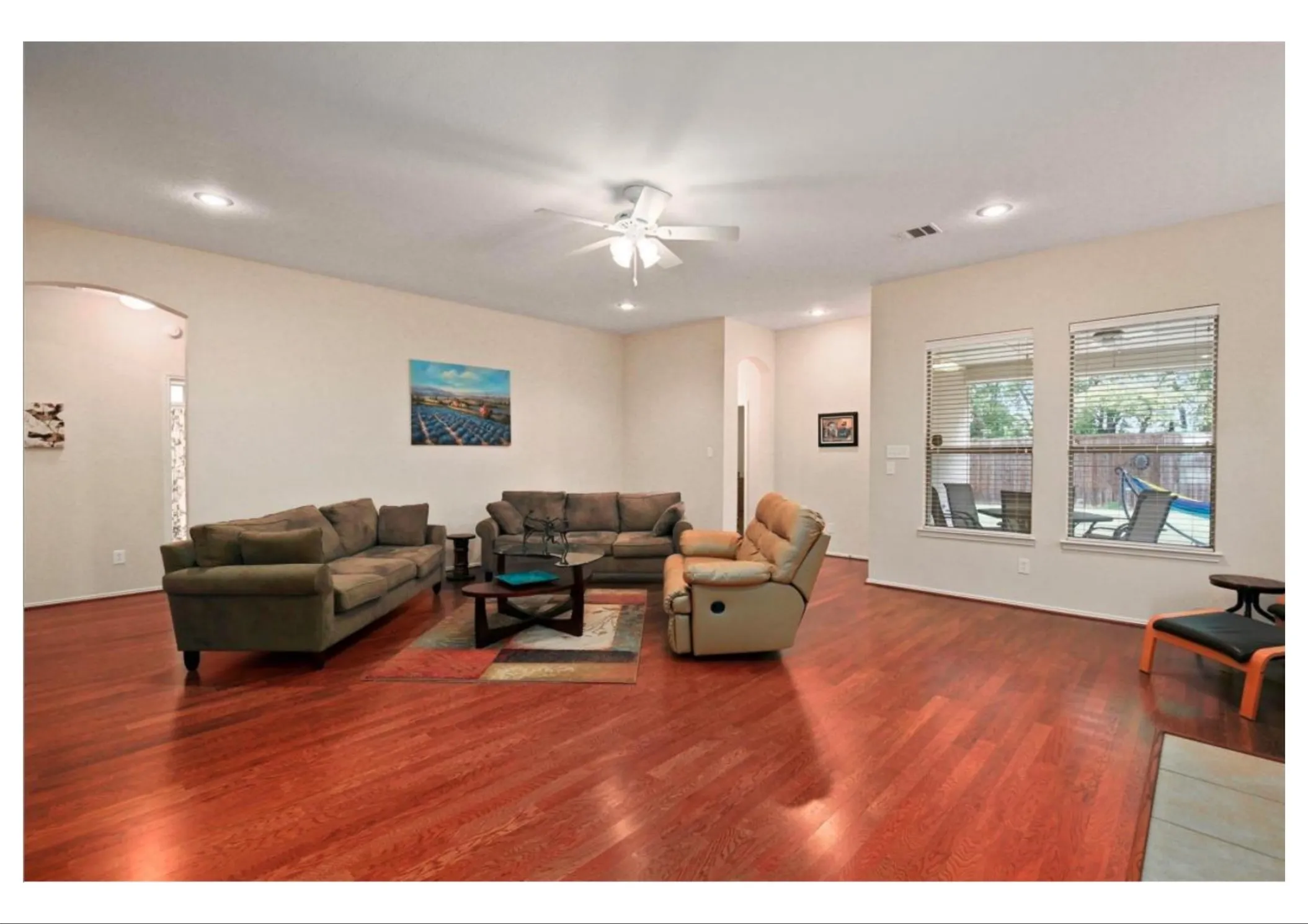 Spacious living area featuring rich wood-finish flooring and neutral wall tones