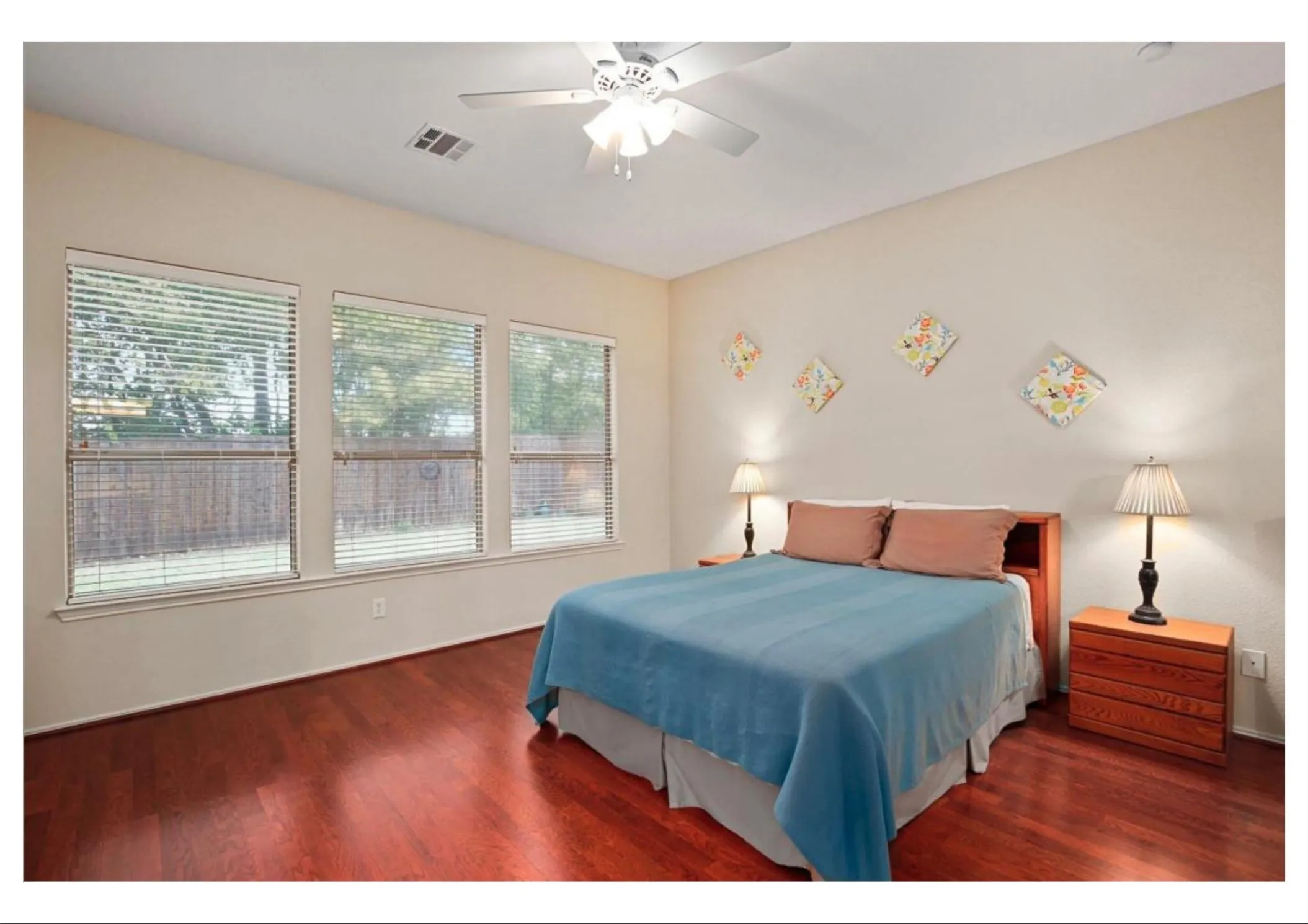 Room featuring rich wood-finish flooring, three large windows with blinds, a ceiling fan, and recessed lighting