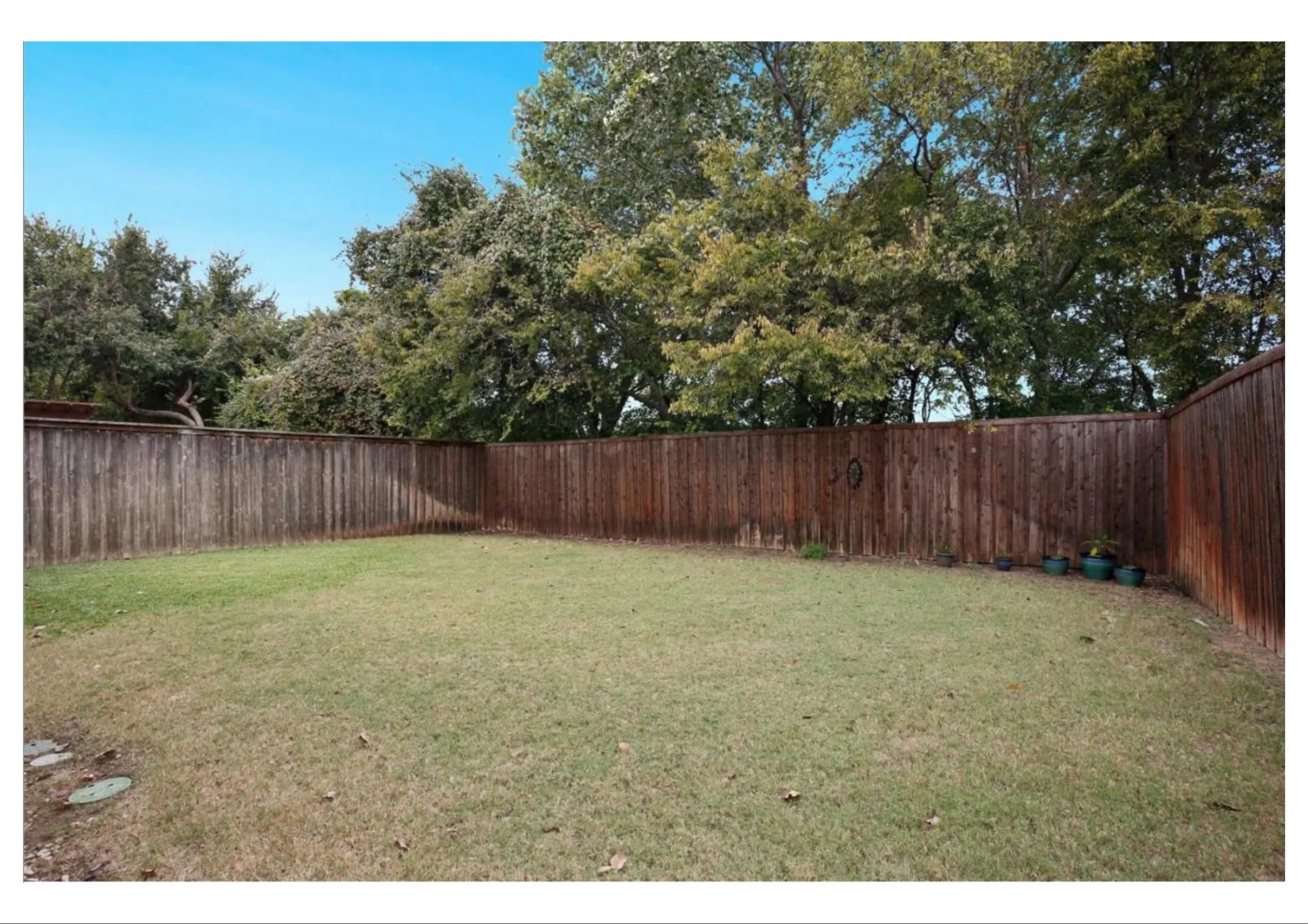 Expansive backyard with a manicured lawn, surrounded by a wood privacy fence