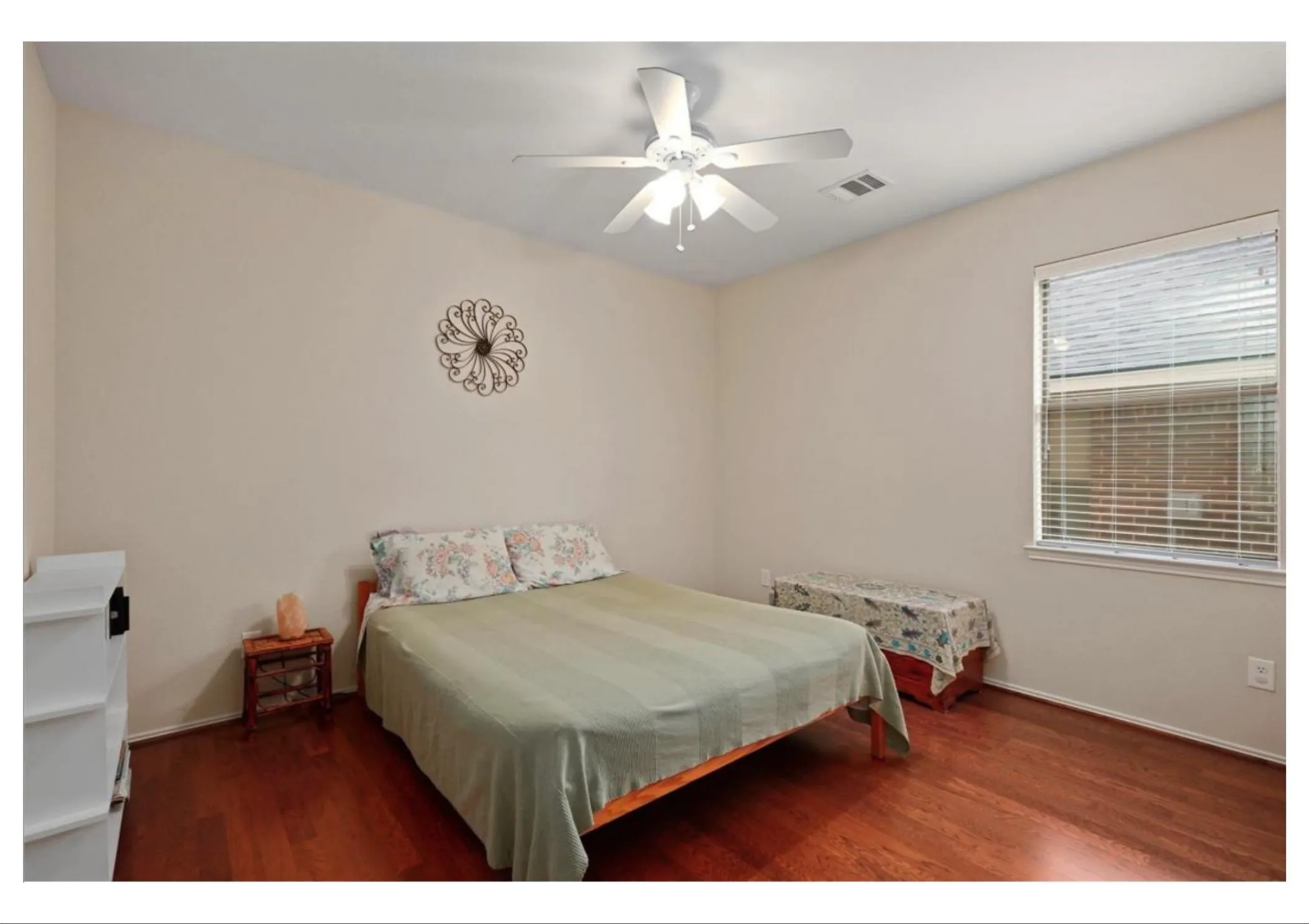 Bedroom featuring wood-finish flooring, a ceiling fan with integrated lighting, and a single window with blinds