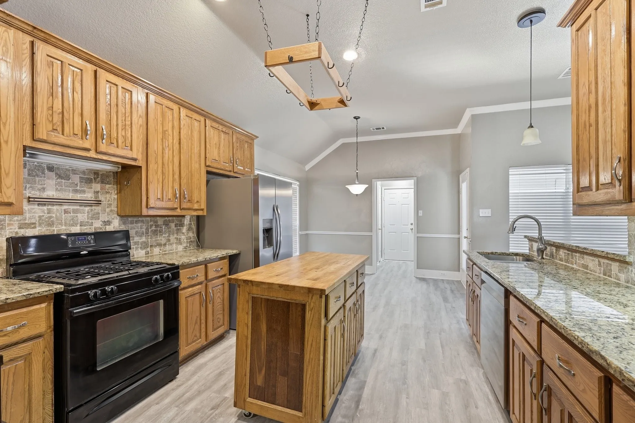 Kitchen featuring extensive wood cabinetry, stone countertops, a tiled backsplash, and light wood-finish flooring