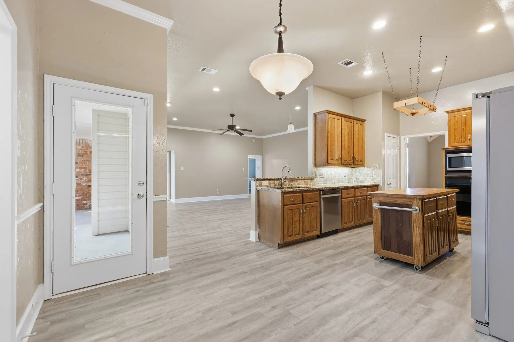 Open-concept kitchen featuring wood-finish cabinetry, stainless steel appliances, a center island, and wood-finish flooring