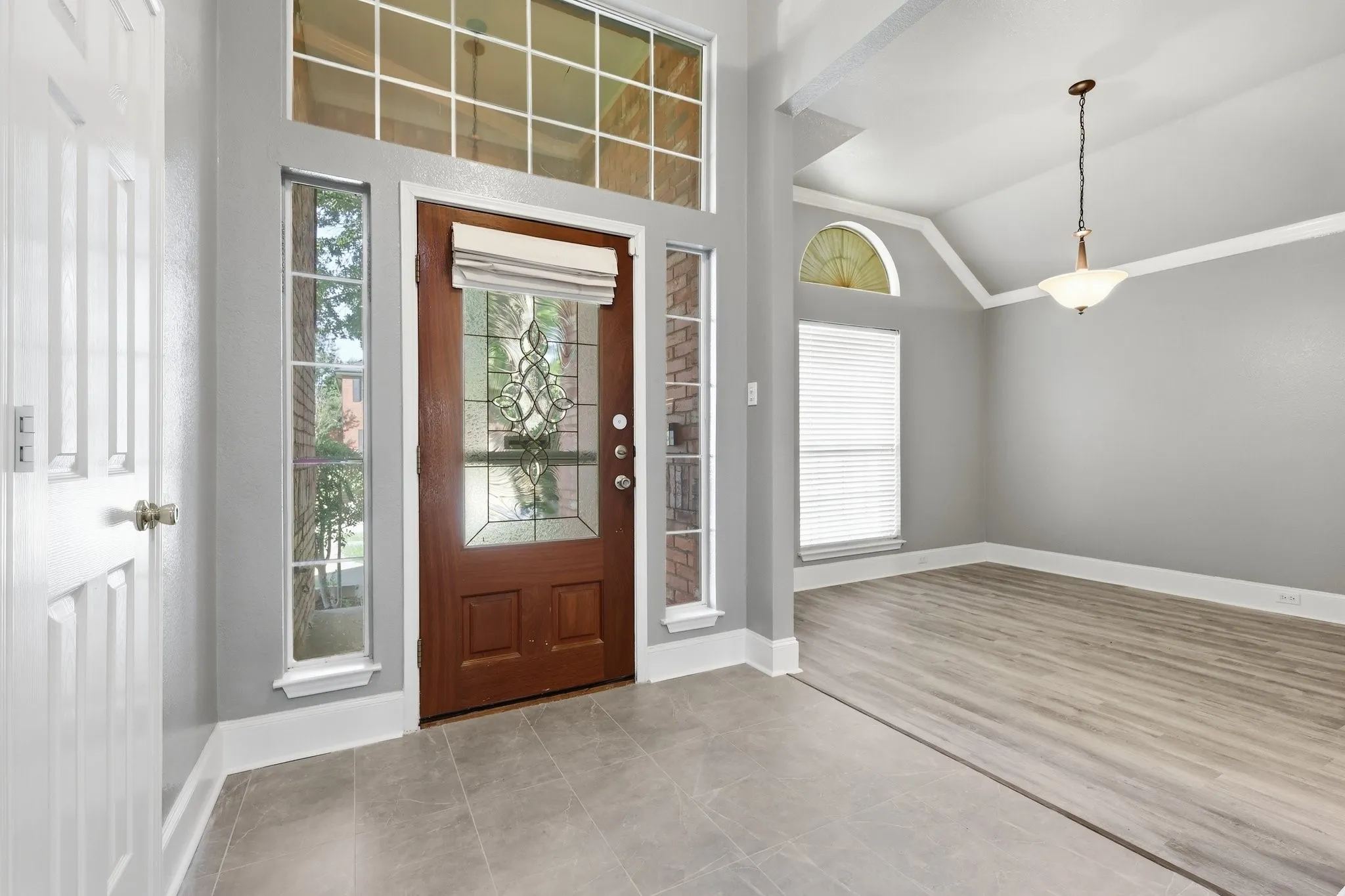 Entry foyer featuring a wood-panel door with decorative glass inserts, transom window, and sidelights
