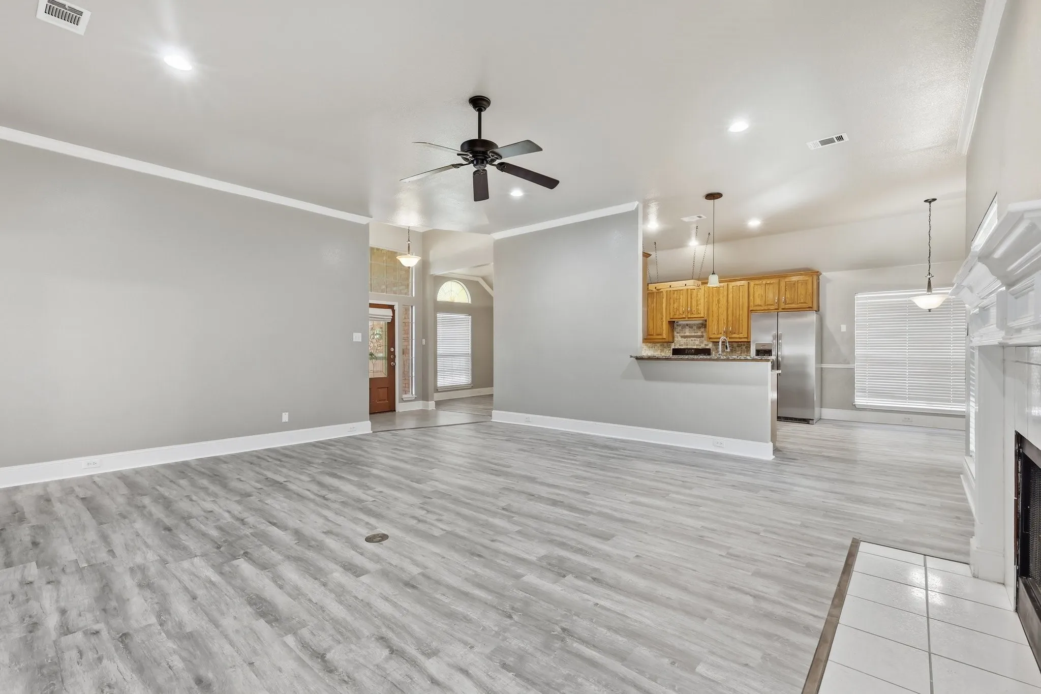 Spacious main living area featuring light wood-finish flooring, vaulted ceilings, and crown molding