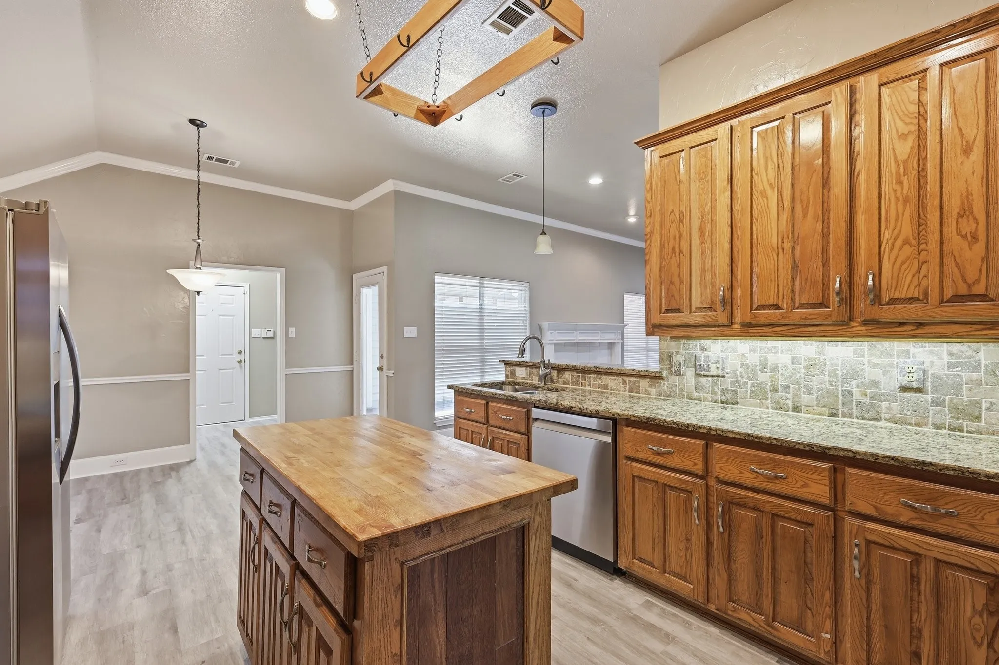 Kitchen featuring wood-finish cabinetry, granite countertops, and a mosaic tile backsplash