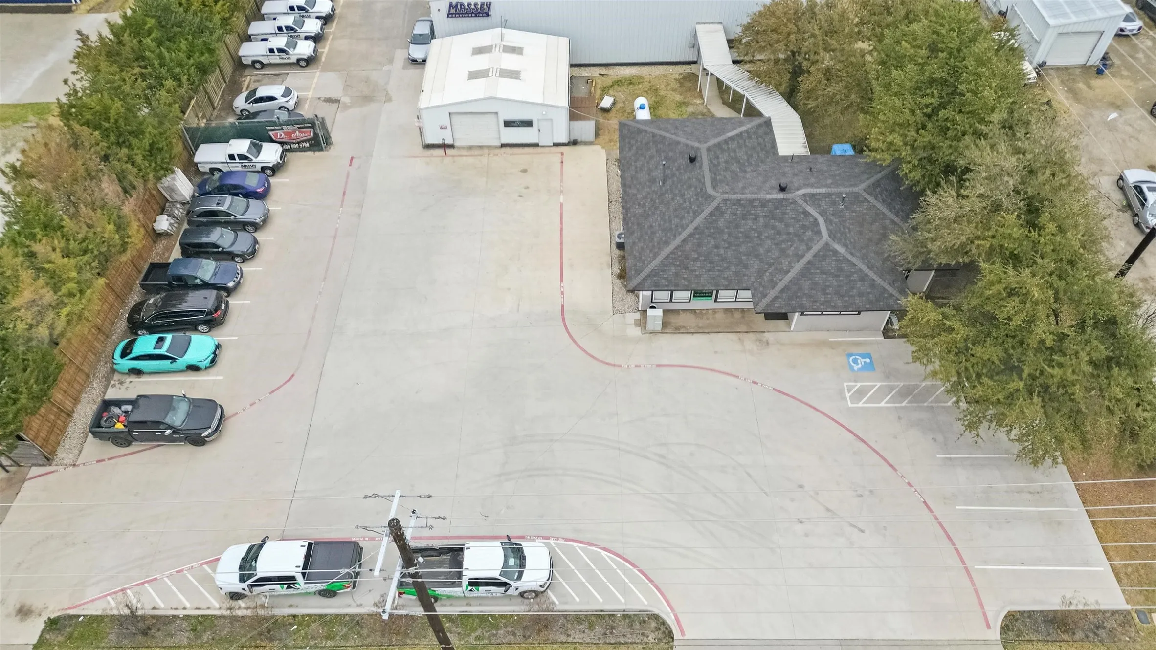 Spacious commercial property featuring a paved parking lot with marked spaces, a multi-gabled roofline, and established perimeter trees