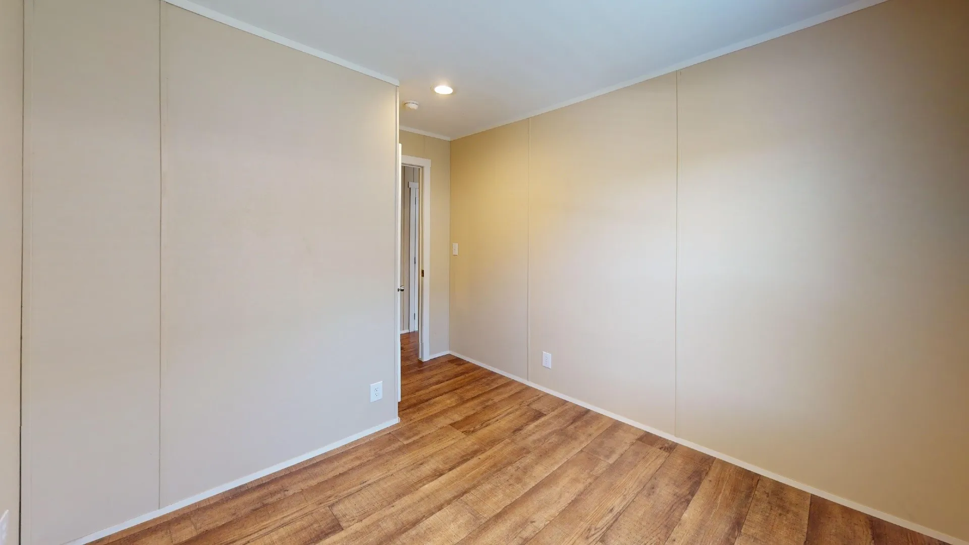 Room featuring wood-finish flooring, light-toned wall paneling, and white trim