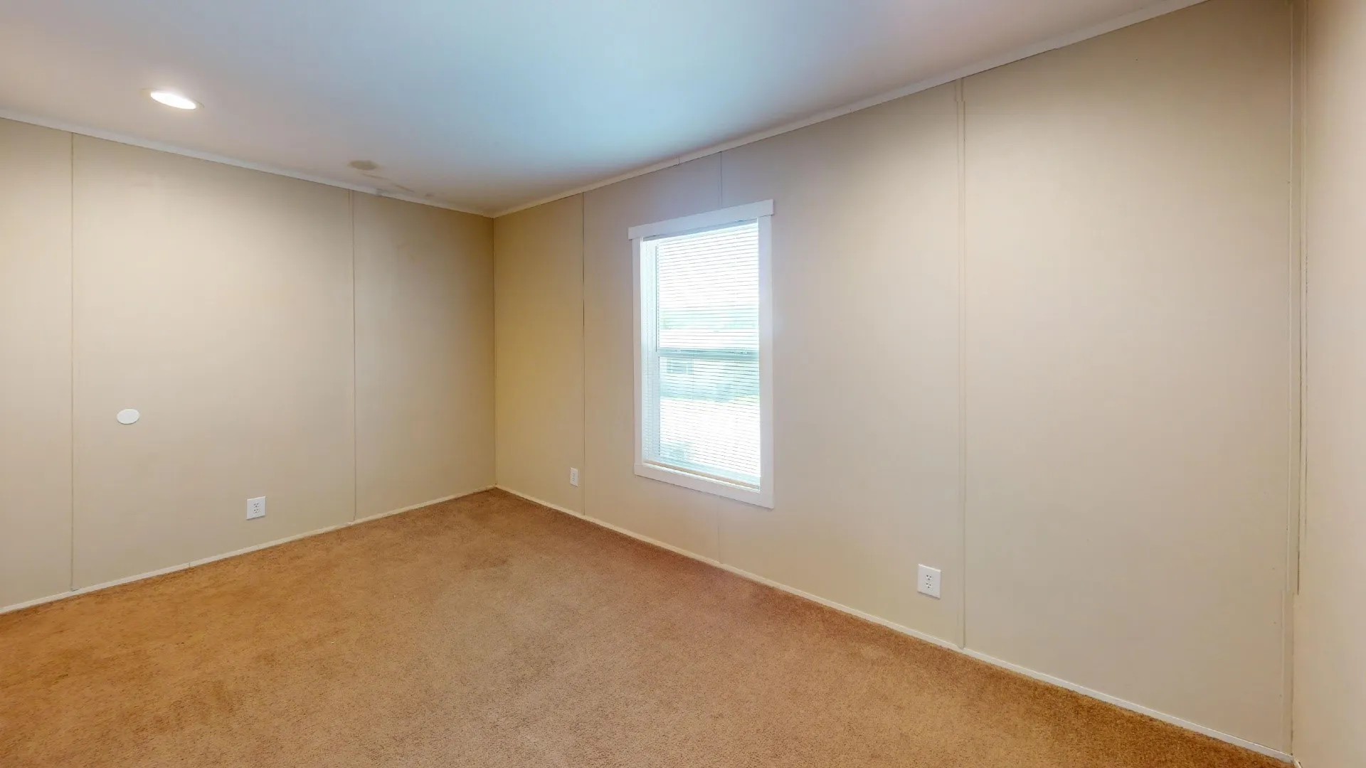 Neutral-toned room featuring a single window and recessed lighting