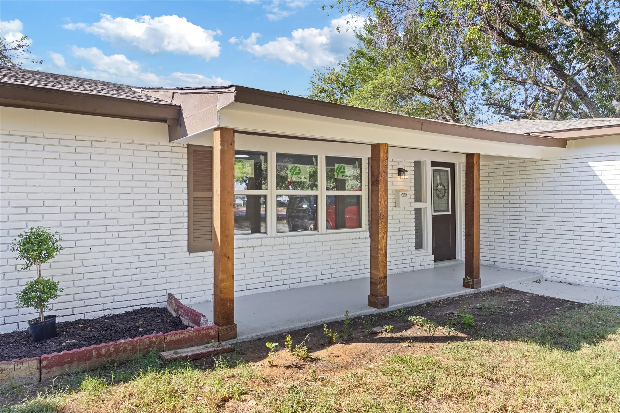 White brick exterior featuring a covered porch with natural wood support posts