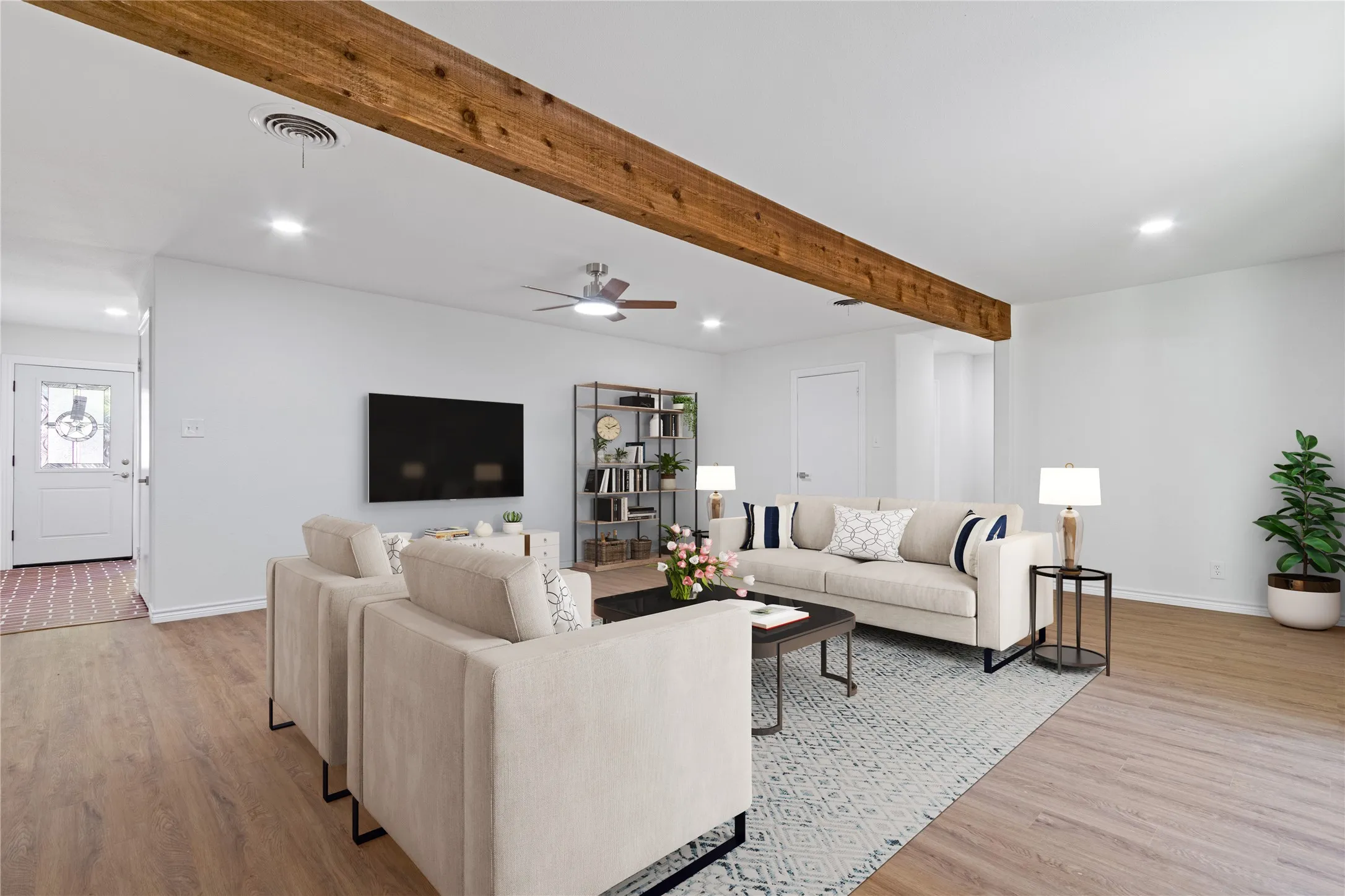 Spacious room featuring wood-finish flooring, a ceiling fan with integrated lighting, and two windows providing natural light