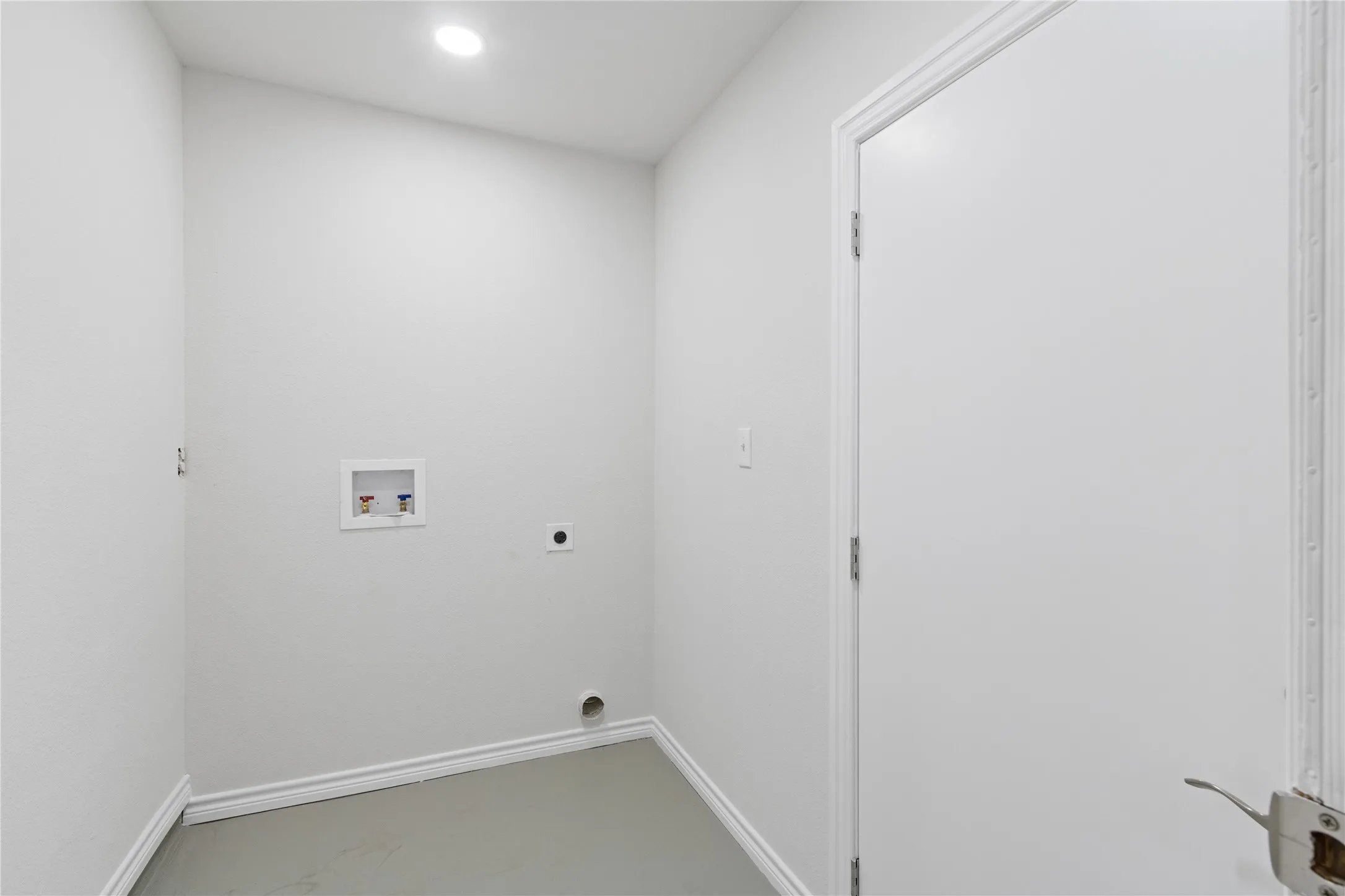 Dedicated laundry area featuring a white door, light gray walls, white baseboards, and a recessed ceiling light