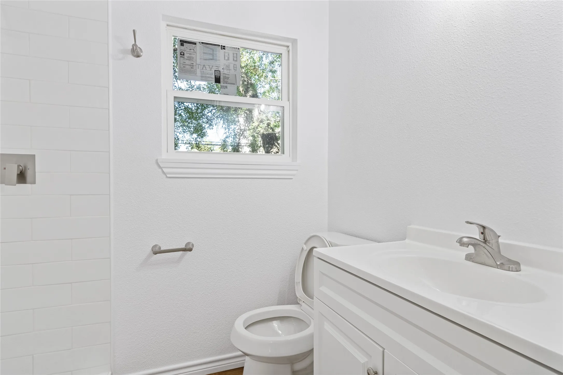 Bathroom featuring a white vanity with integrated sink, chrome faucet, and white subway tile shower surround