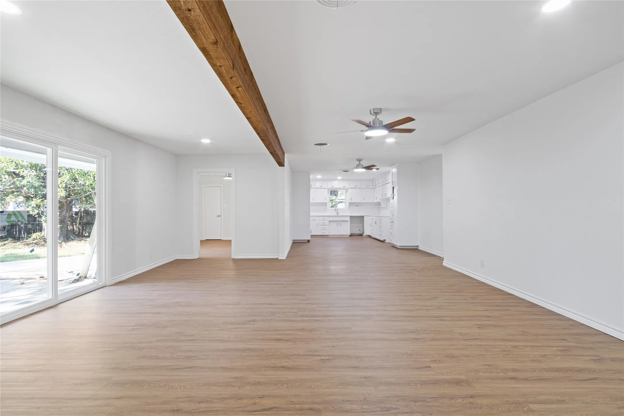 Expansive main living area featuring wood-finish flooring and a prominent exposed wood beam