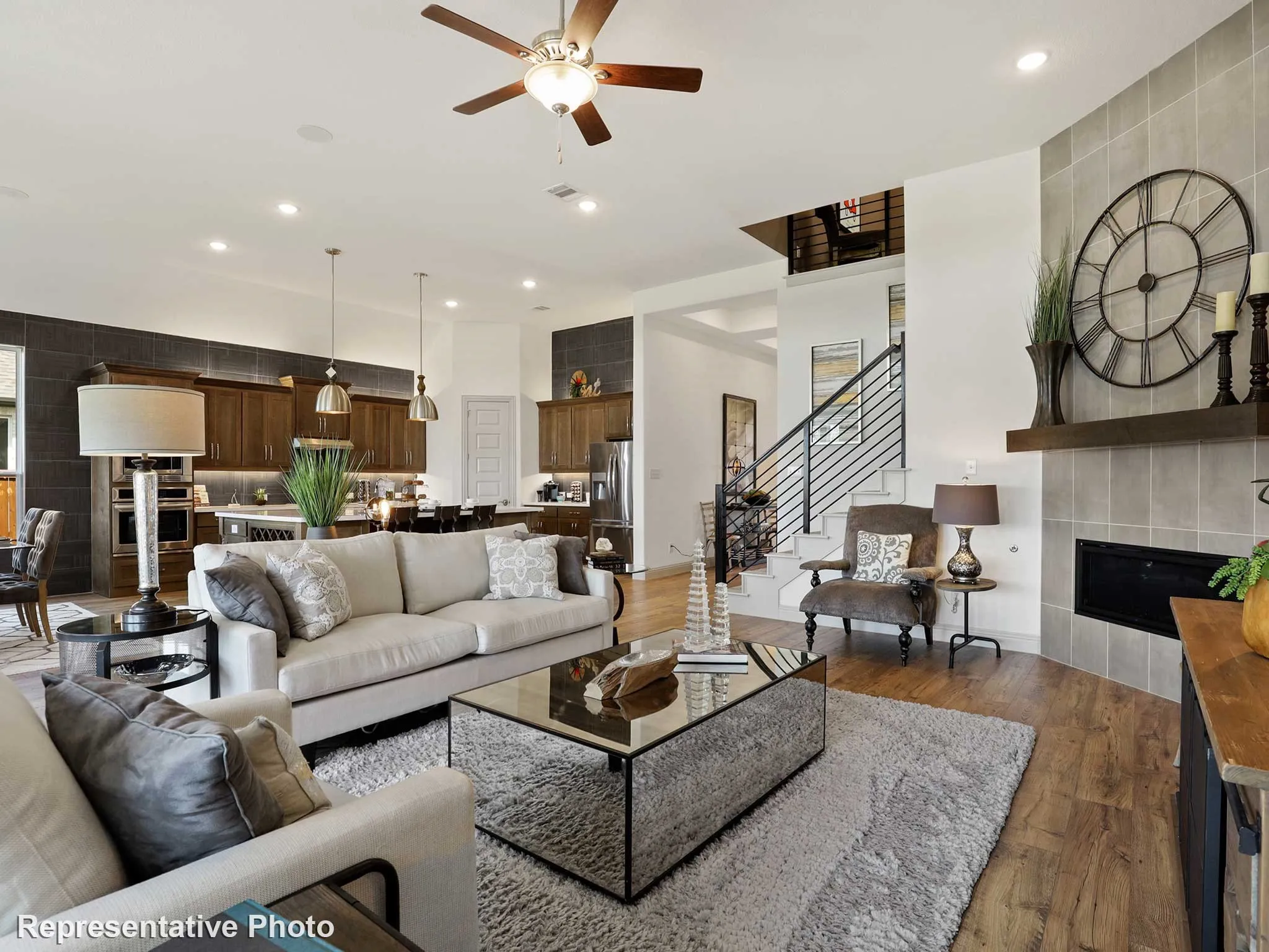 Spacious living area featuring wood-finish flooring, a tiled fireplace with a wood mantel, and an open-concept design