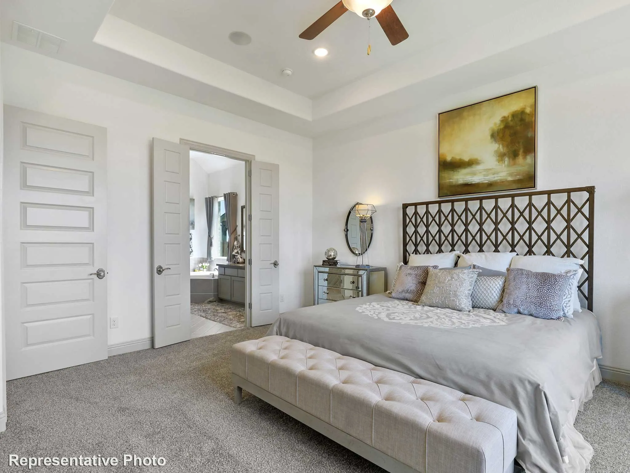 Carpeted sleeping area with a tray ceiling and ceiling fan