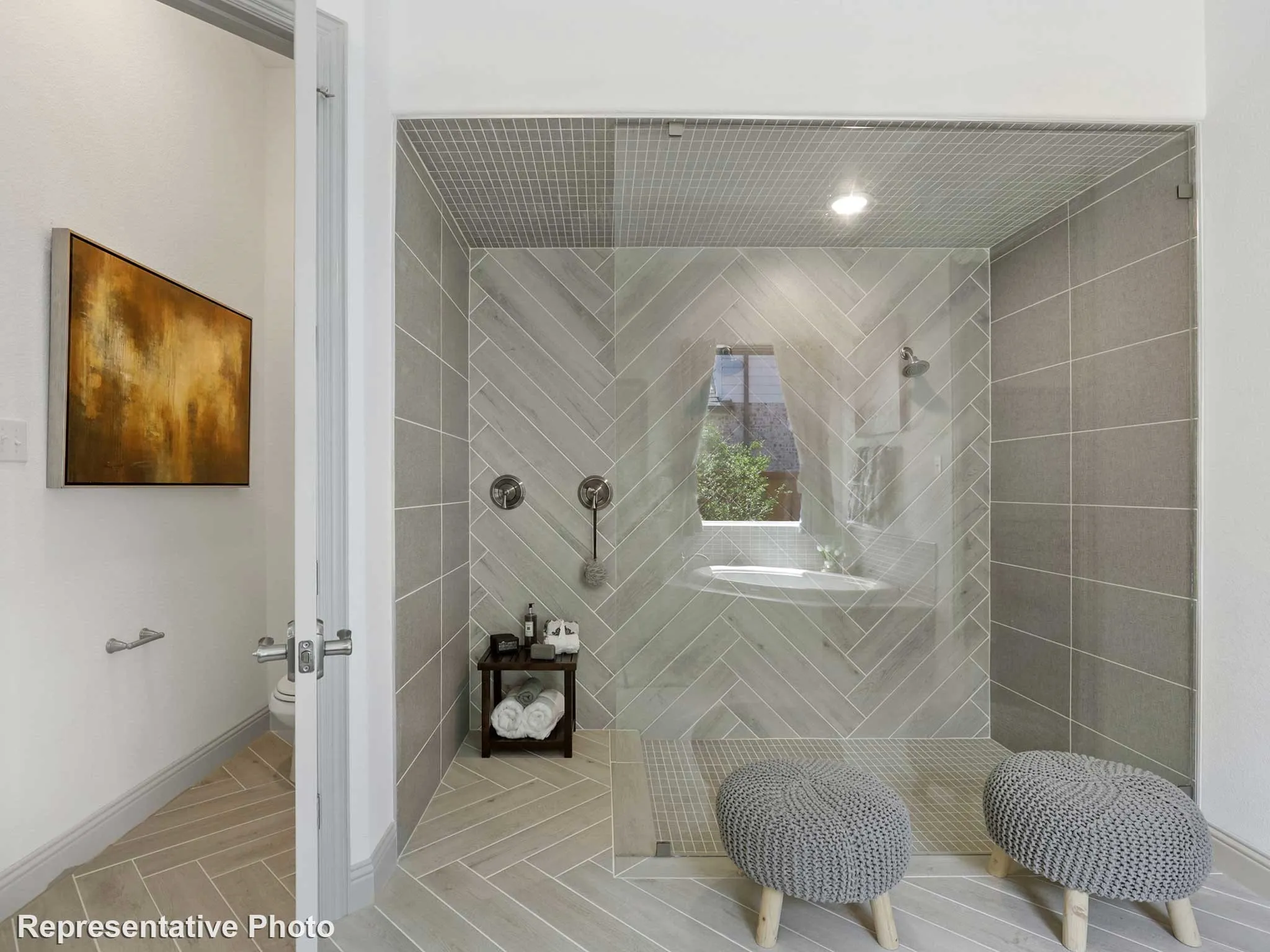 Spacious shower enclosure featuring herringbone-patterned wall tile, glass shower panel, and a built-in shelf