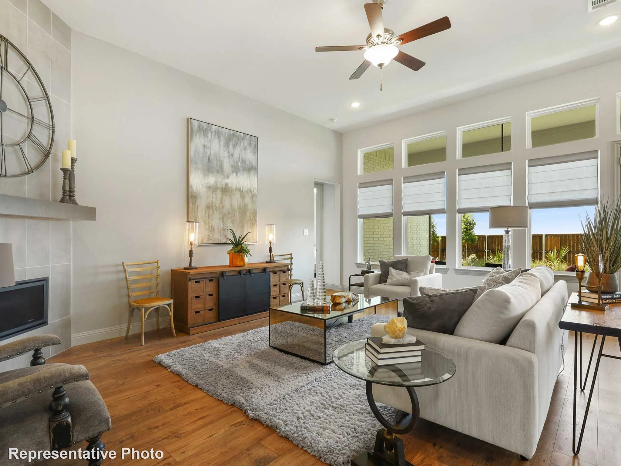 Spacious living area featuring high ceilings, wood-finish flooring, and a ceiling fan with integrated lighting