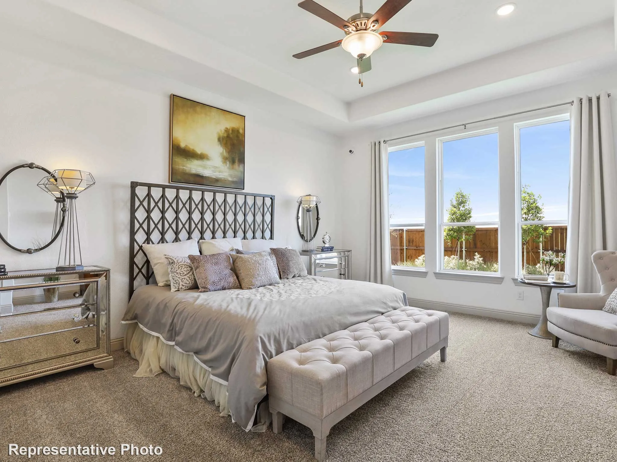 Carpeted room featuring a tray ceiling with a ceiling fan, a large window array, and a dark metal headboard