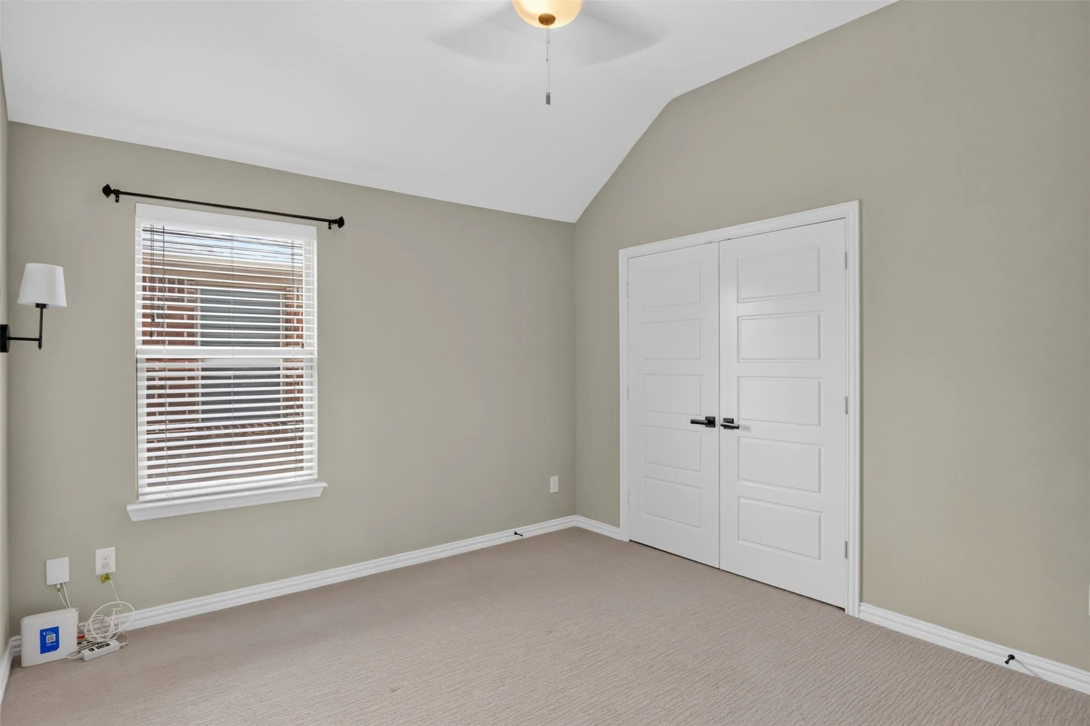 Room with vaulted ceiling, neutral wall paint, and light-colored carpeting