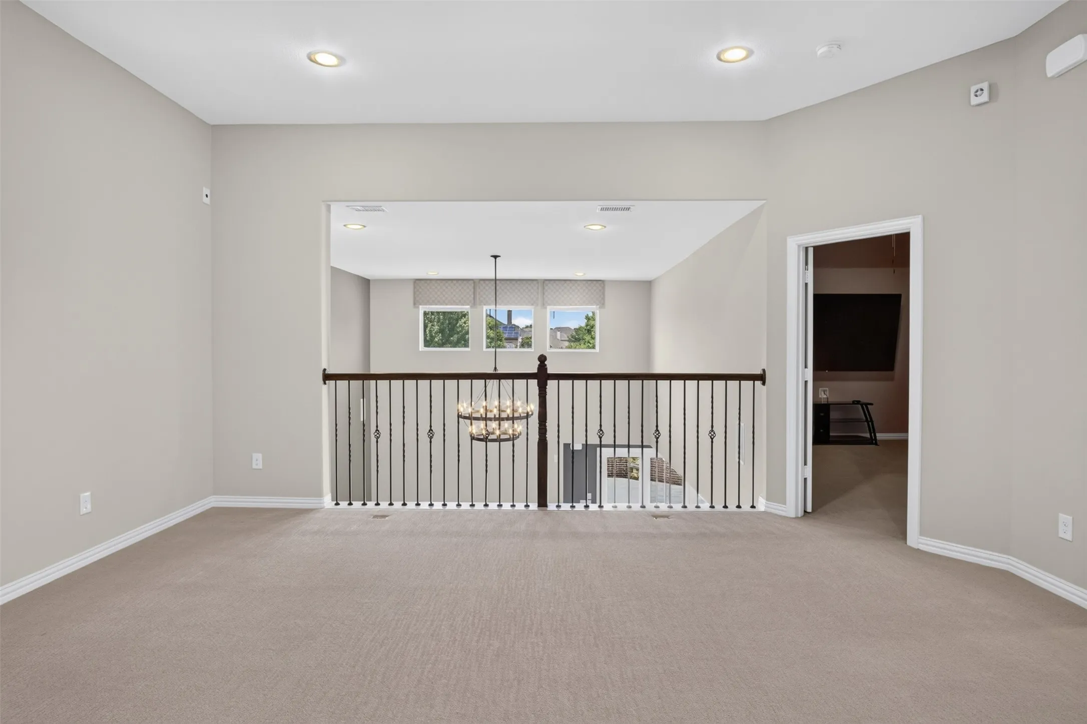 Carpeted loft area featuring a wrought iron and wood-finish railing