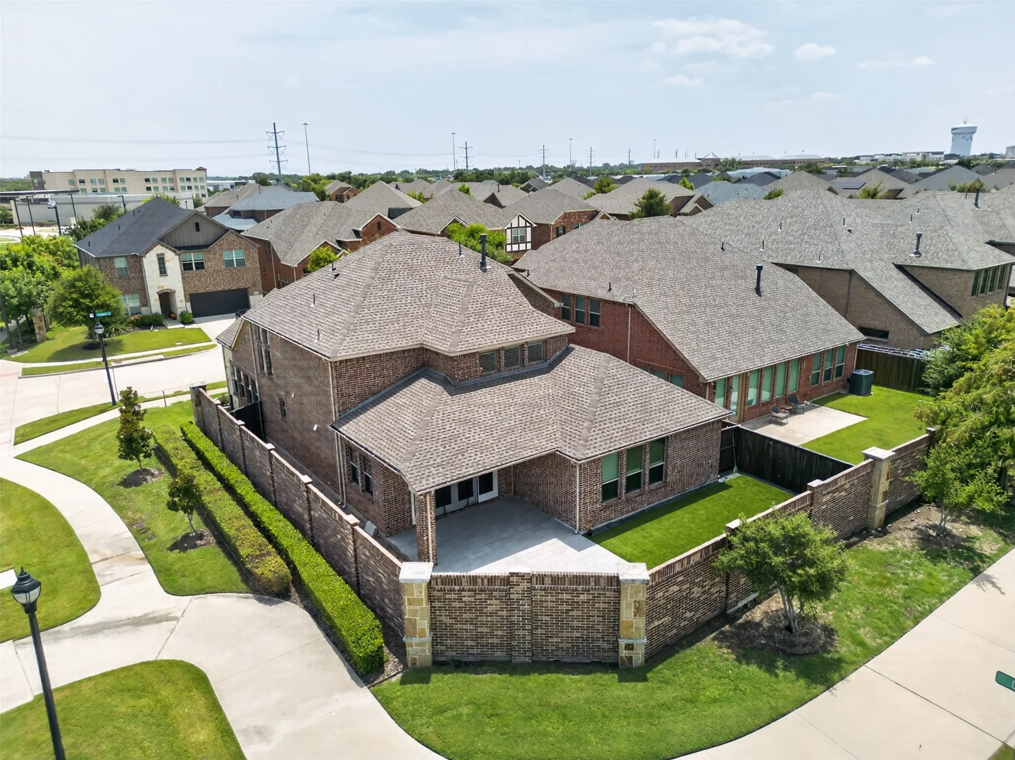 Brick exterior residence featuring a private patio, manicured lawn, and mature landscaping
