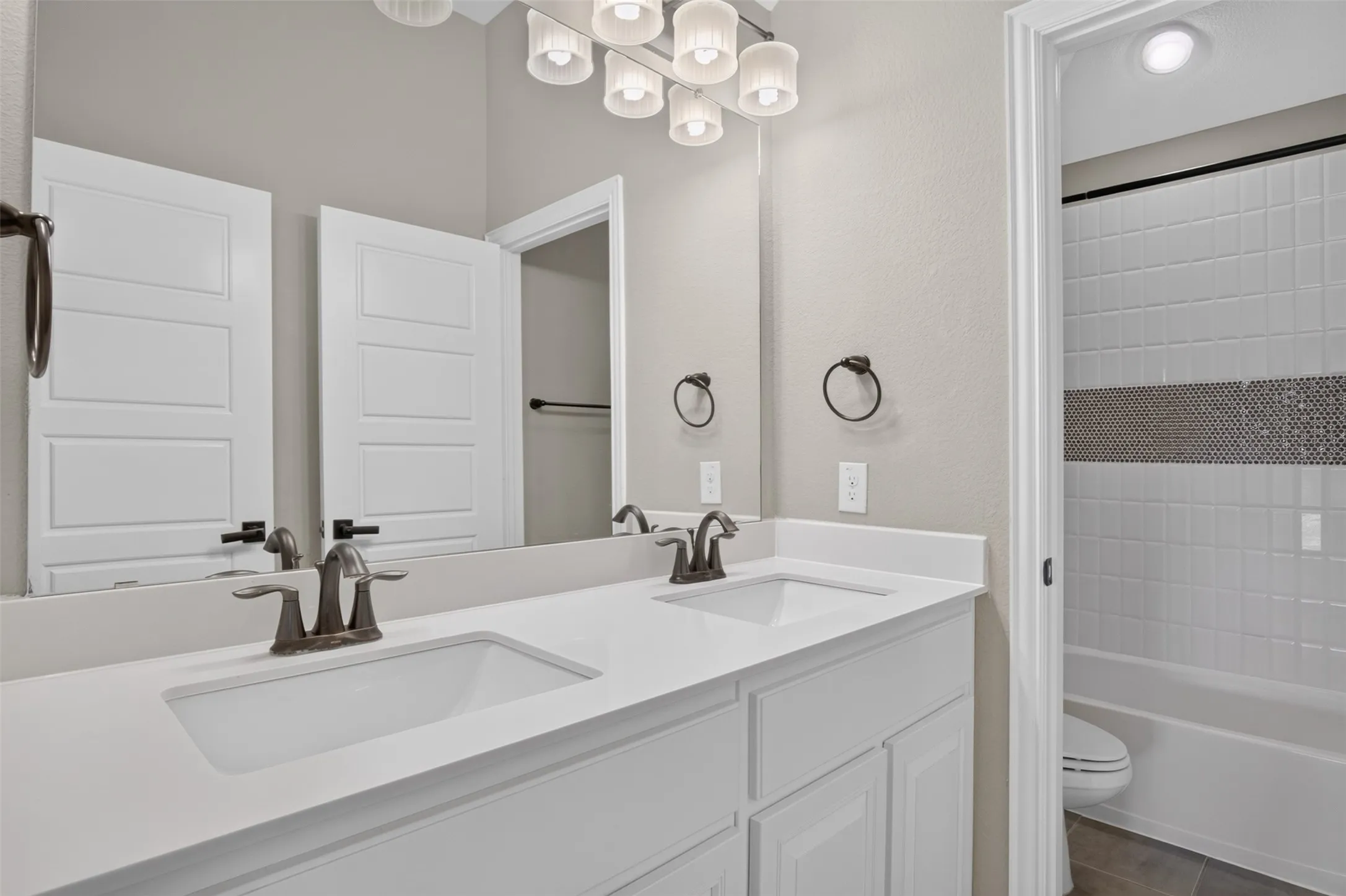 Dual vanity with undermount sinks, bronze finish fixtures, and a large mirror