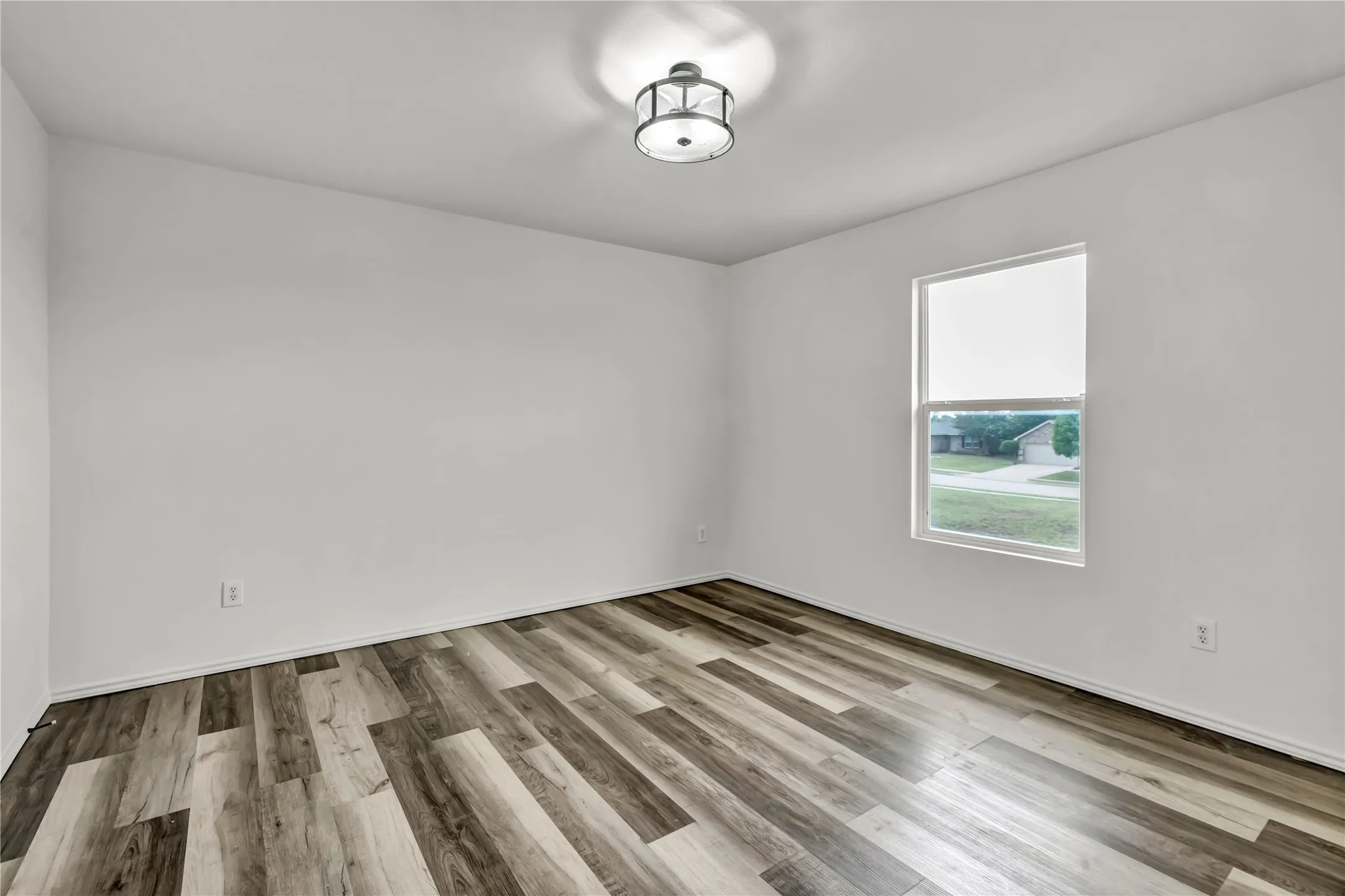 Bright interior room featuring wood-finish flooring, white painted walls, and a contemporary semi-flush mount ceiling light fixture