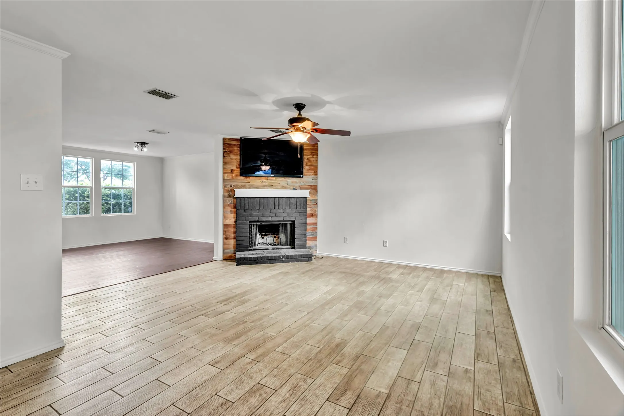 Living area featuring plank-style wood-finish flooring, a ceiling fan, and white walls
