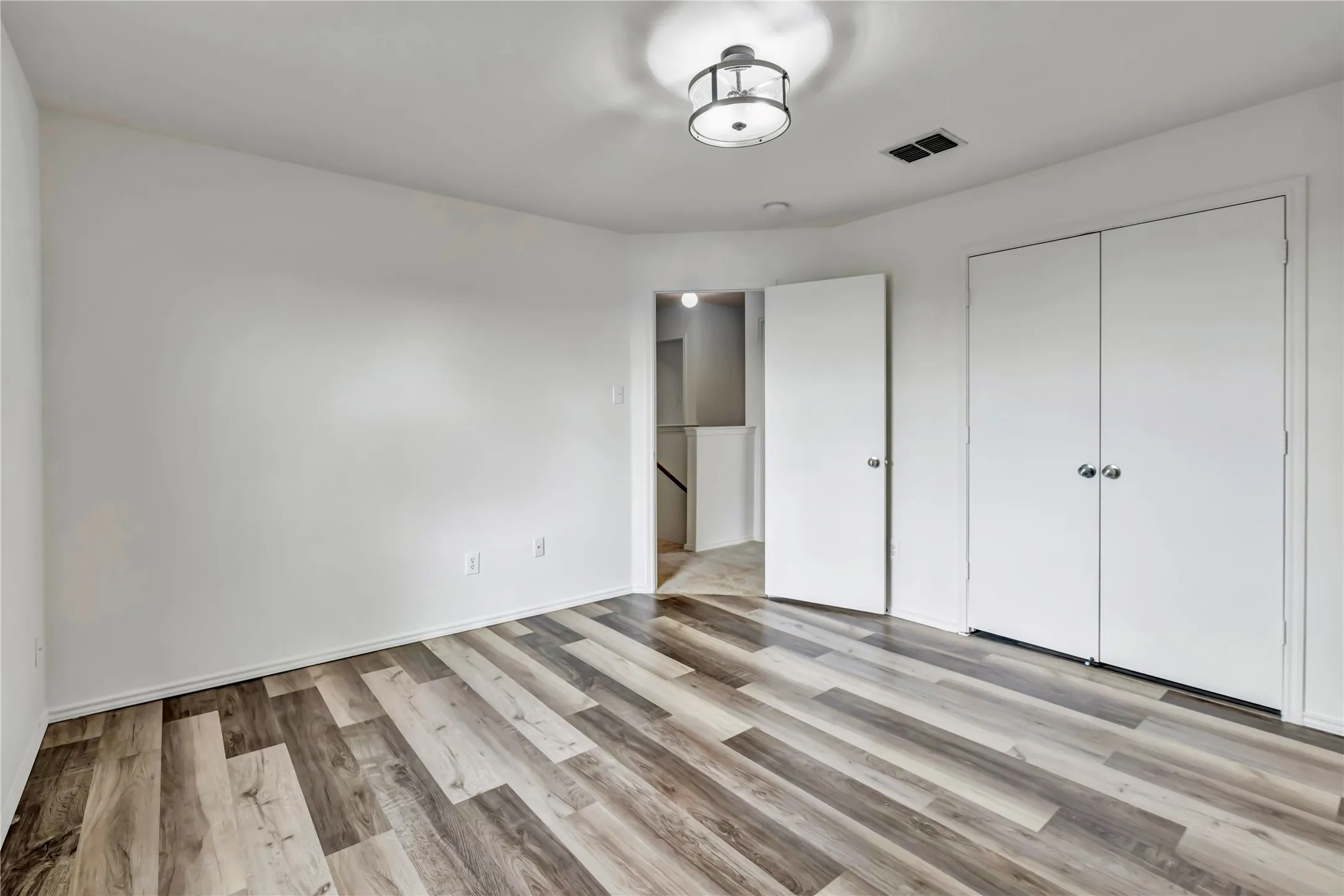 Expansive interior space featuring rich wood-finish flooring and crisp white walls