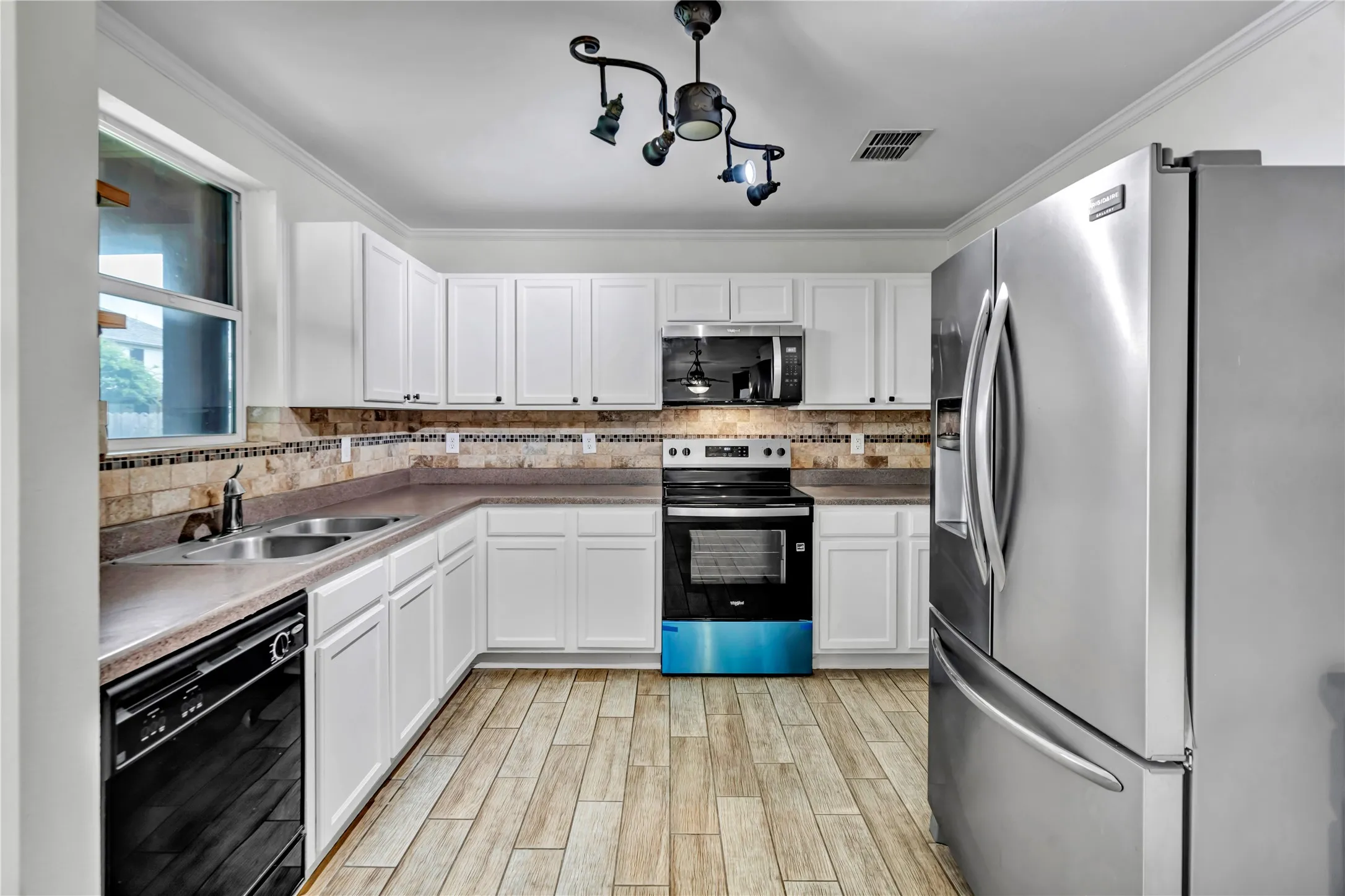 U-shaped kitchen featuring white cabinetry, light wood-finish flooring, and a tiled backsplash