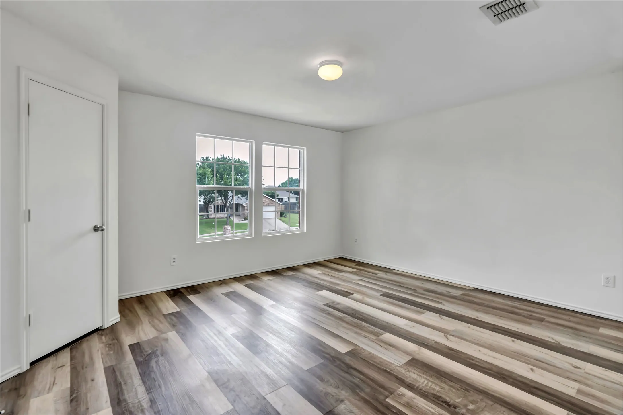 Room featuring wood-finish flooring, white walls, and a ceiling-mounted light fixture