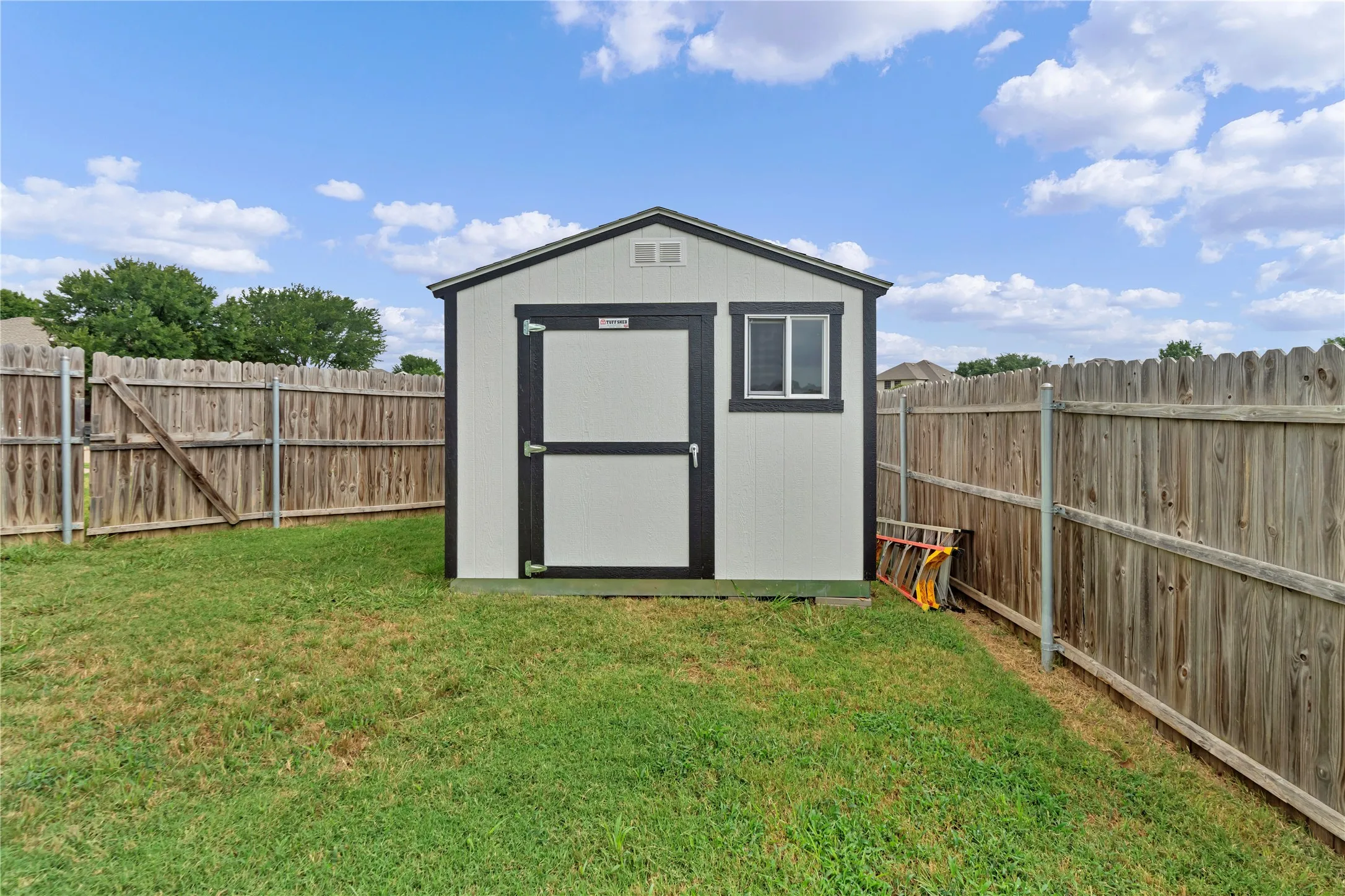 White and dark-trimmed storage shed with a window and double doors