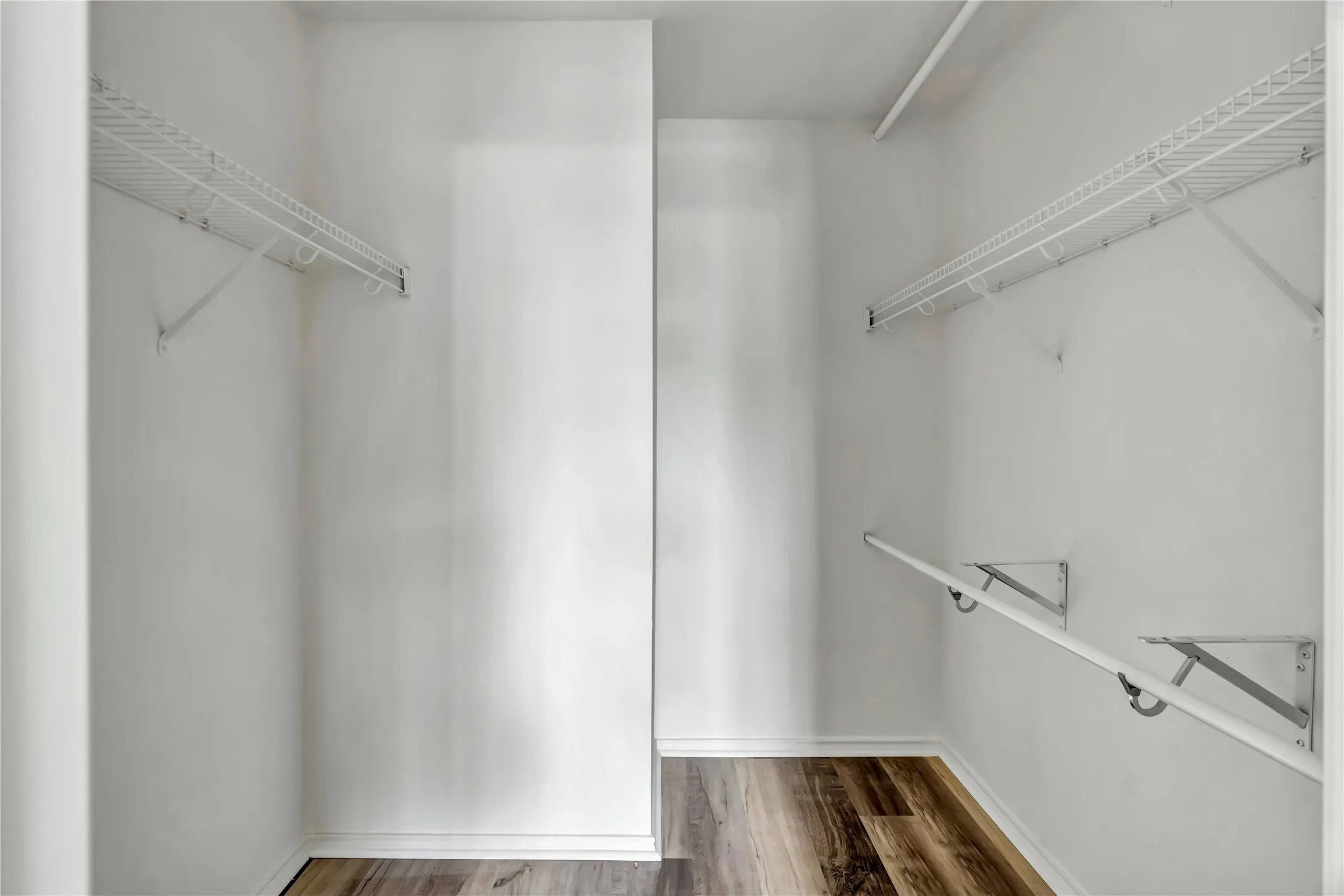 Walk-in closet featuring wood-finish flooring, white walls, and built-in wire shelving