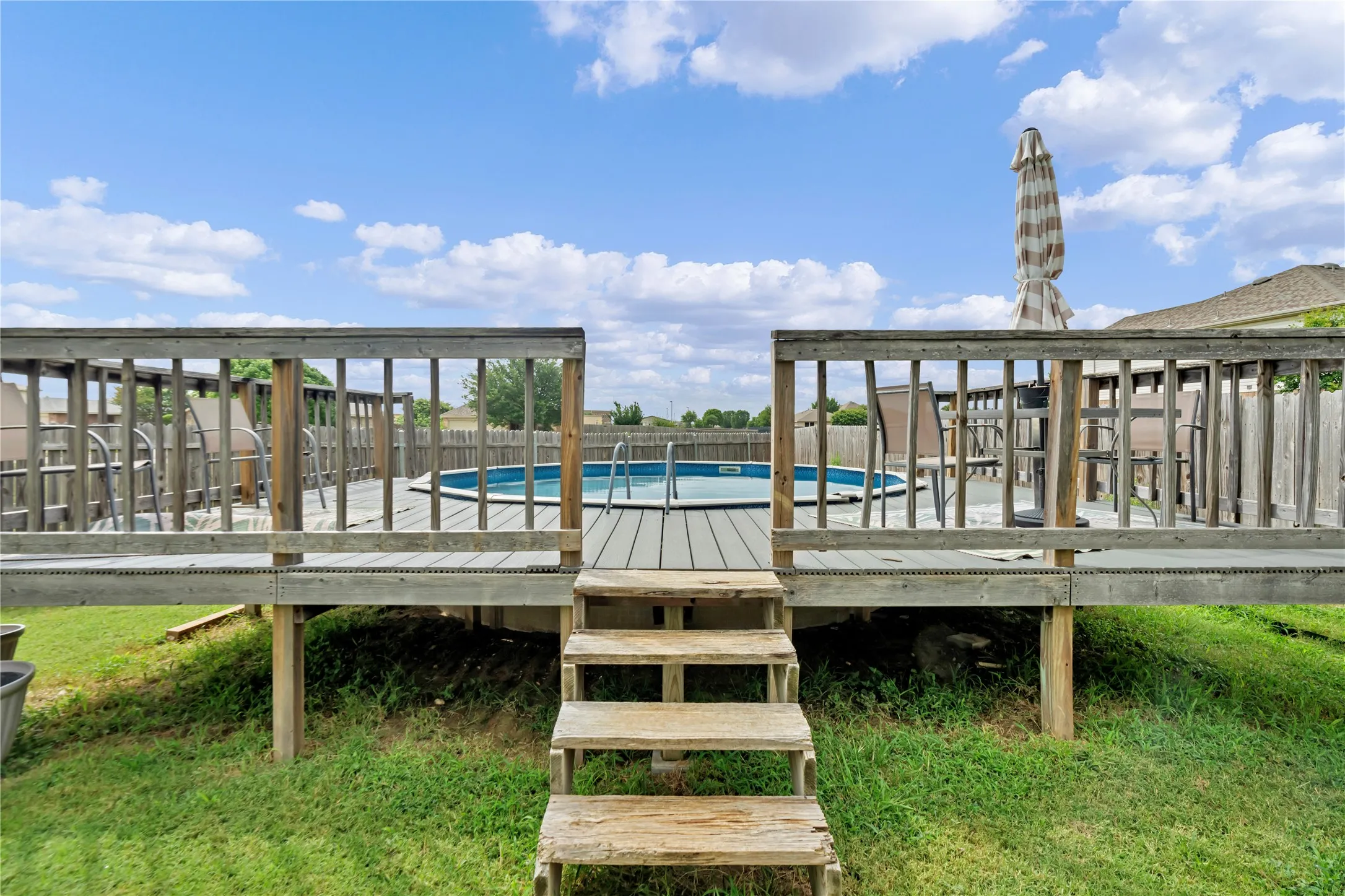 Raised wooden deck featuring a built-in above-ground pool, wood-finish decking, and a perimeter railing